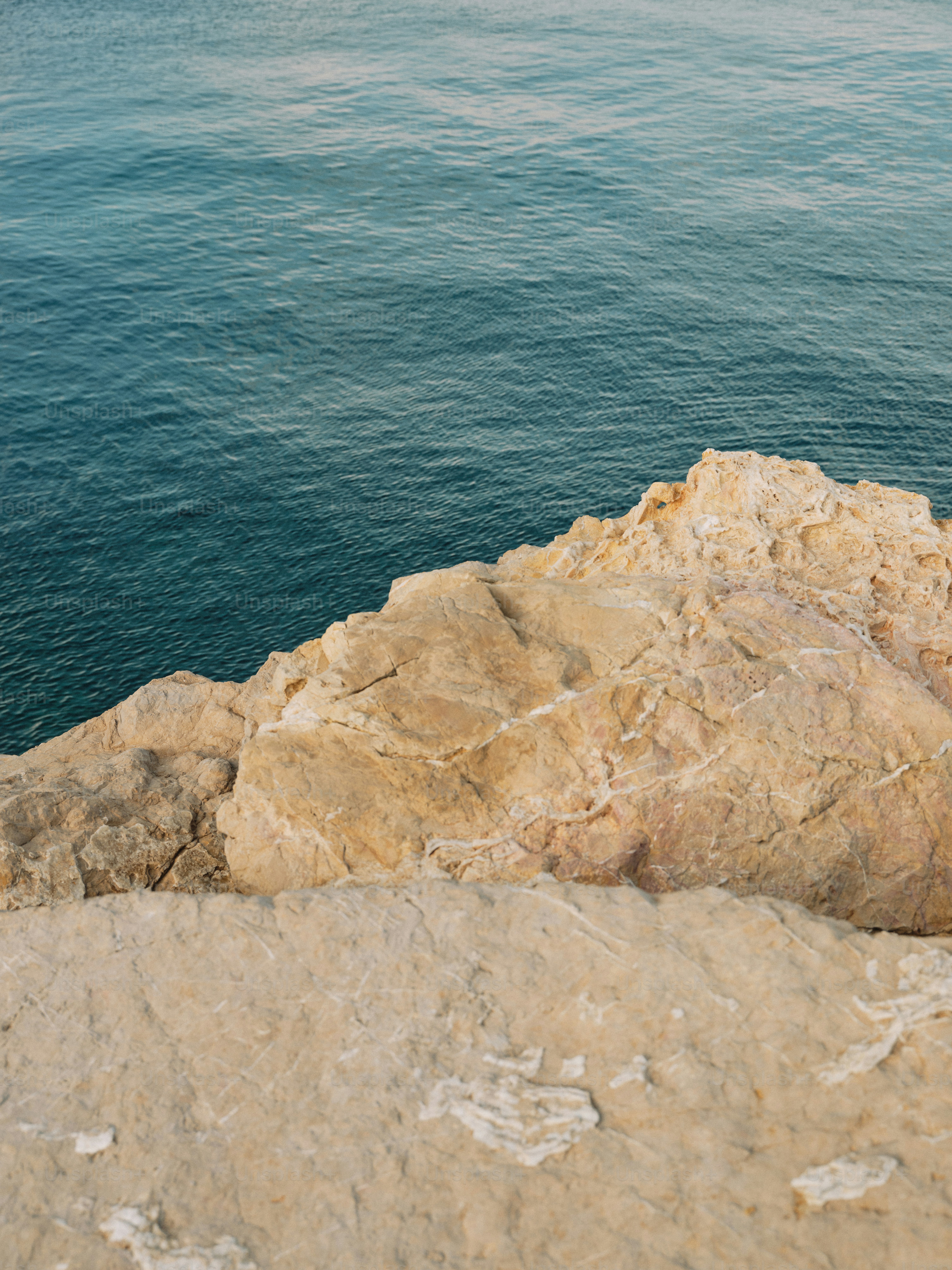 A man sitting on top of a rock next to the ocean