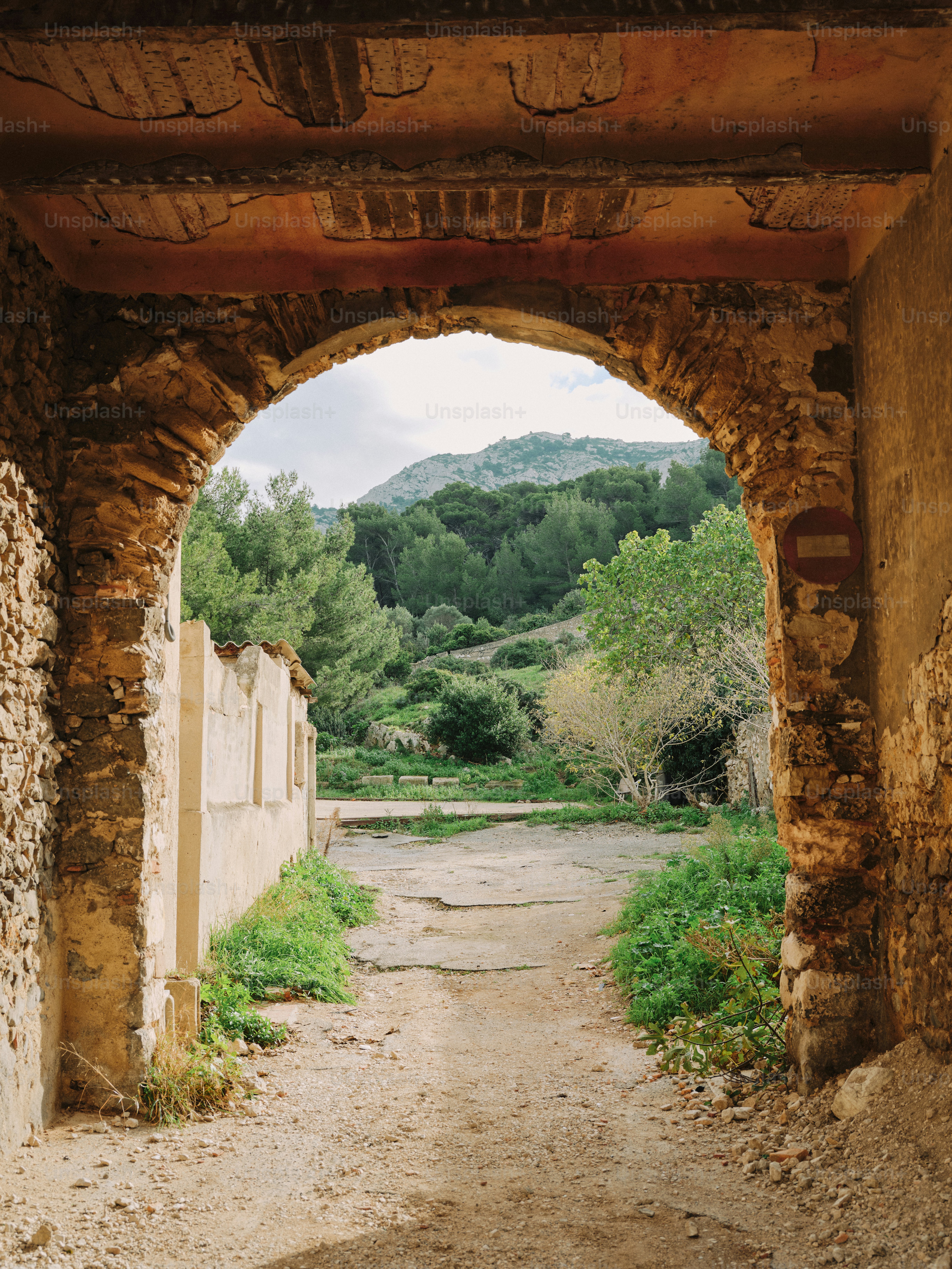 A stone archway with a dirt path leading into the distance