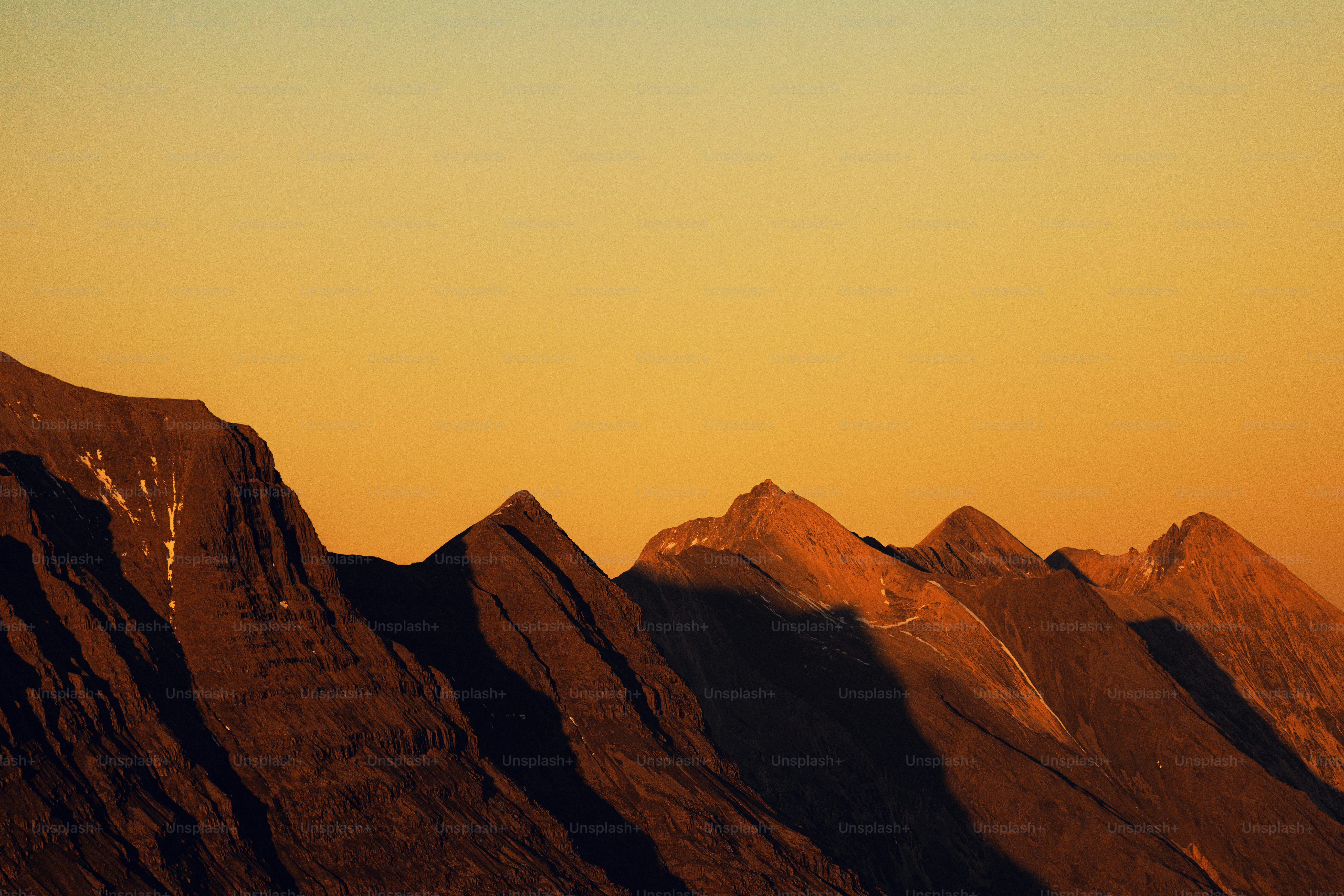 A plane flying over a mountain range at sunset