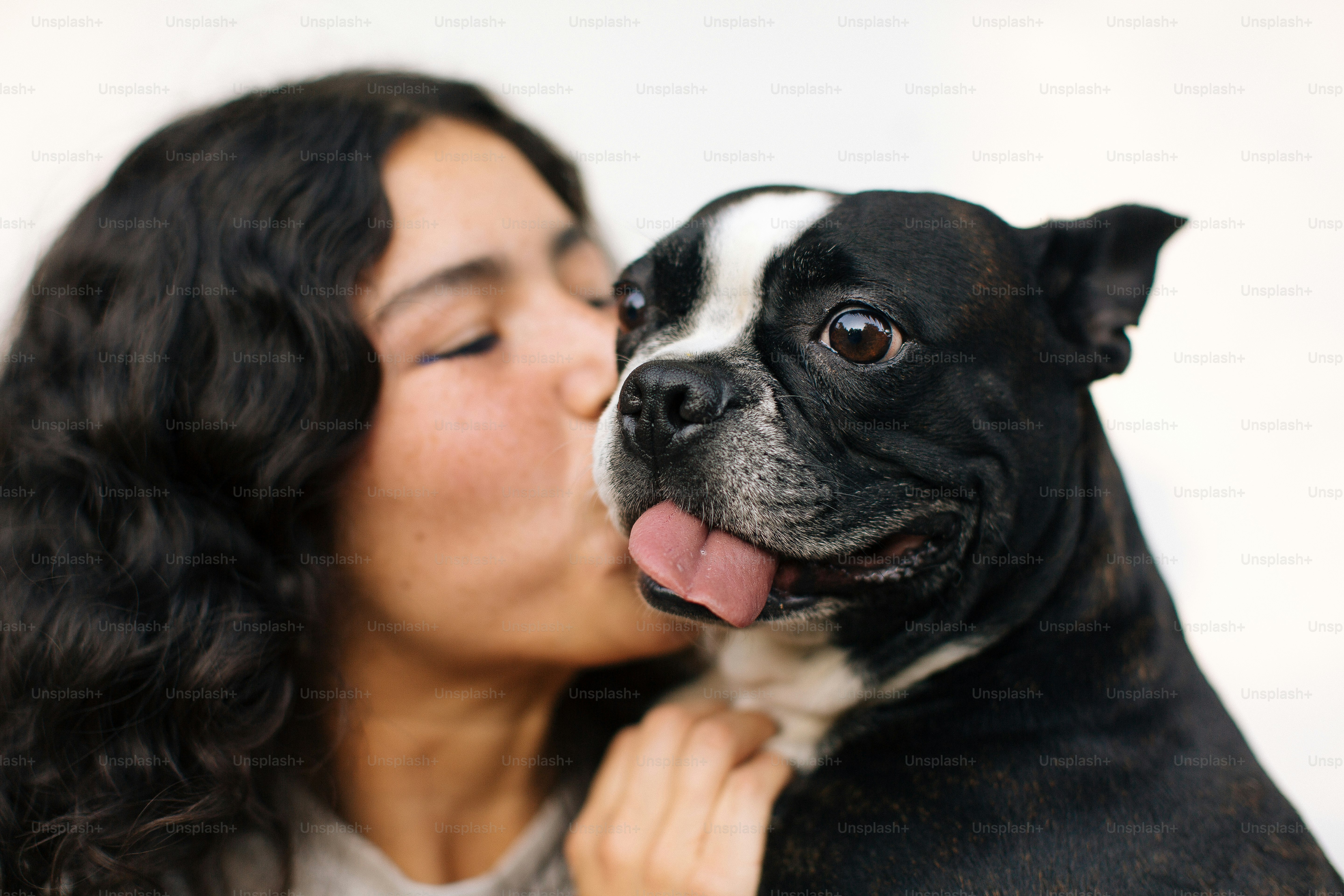 A woman kissing a black and white dog