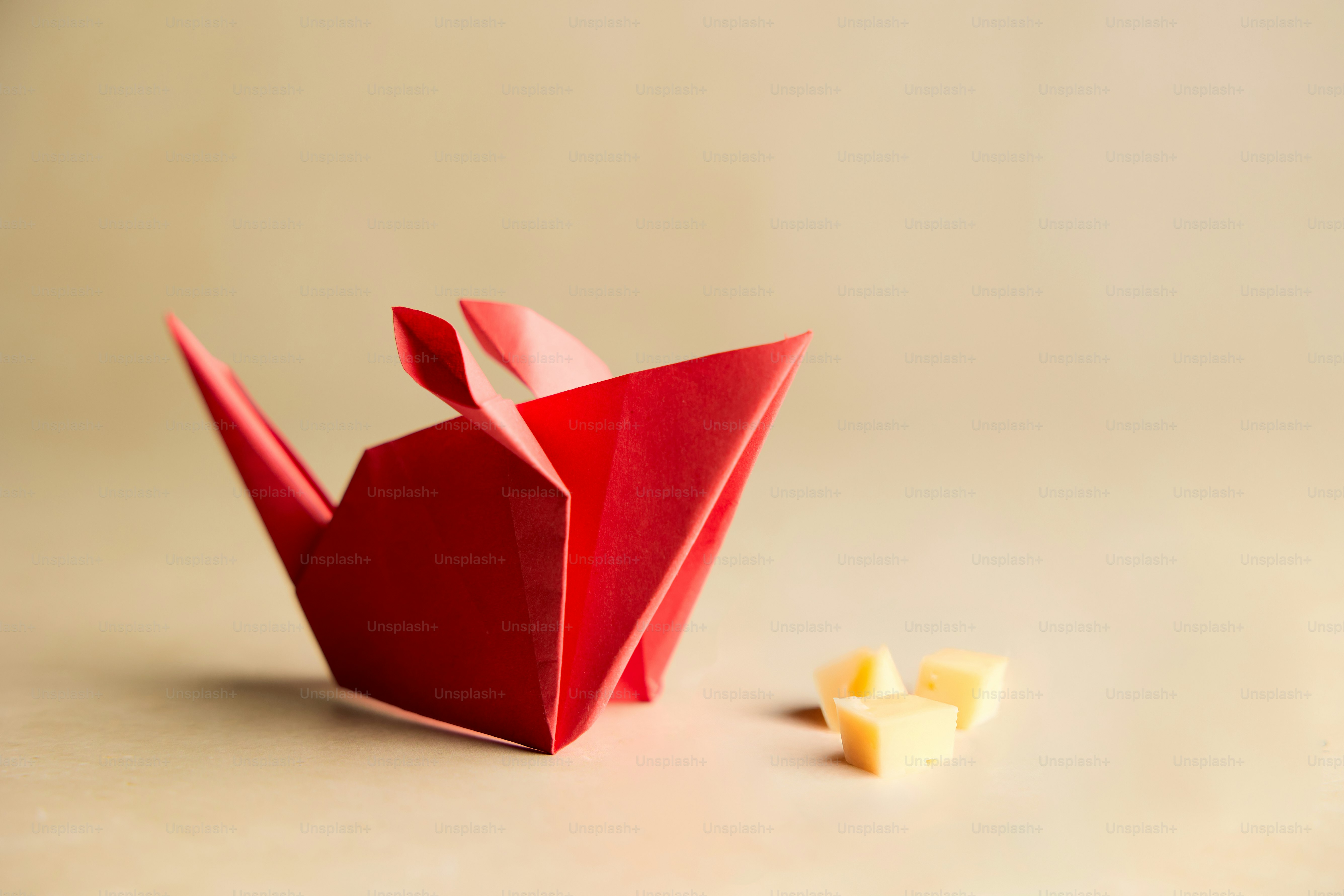 A red origami bird next to a piece of cheese