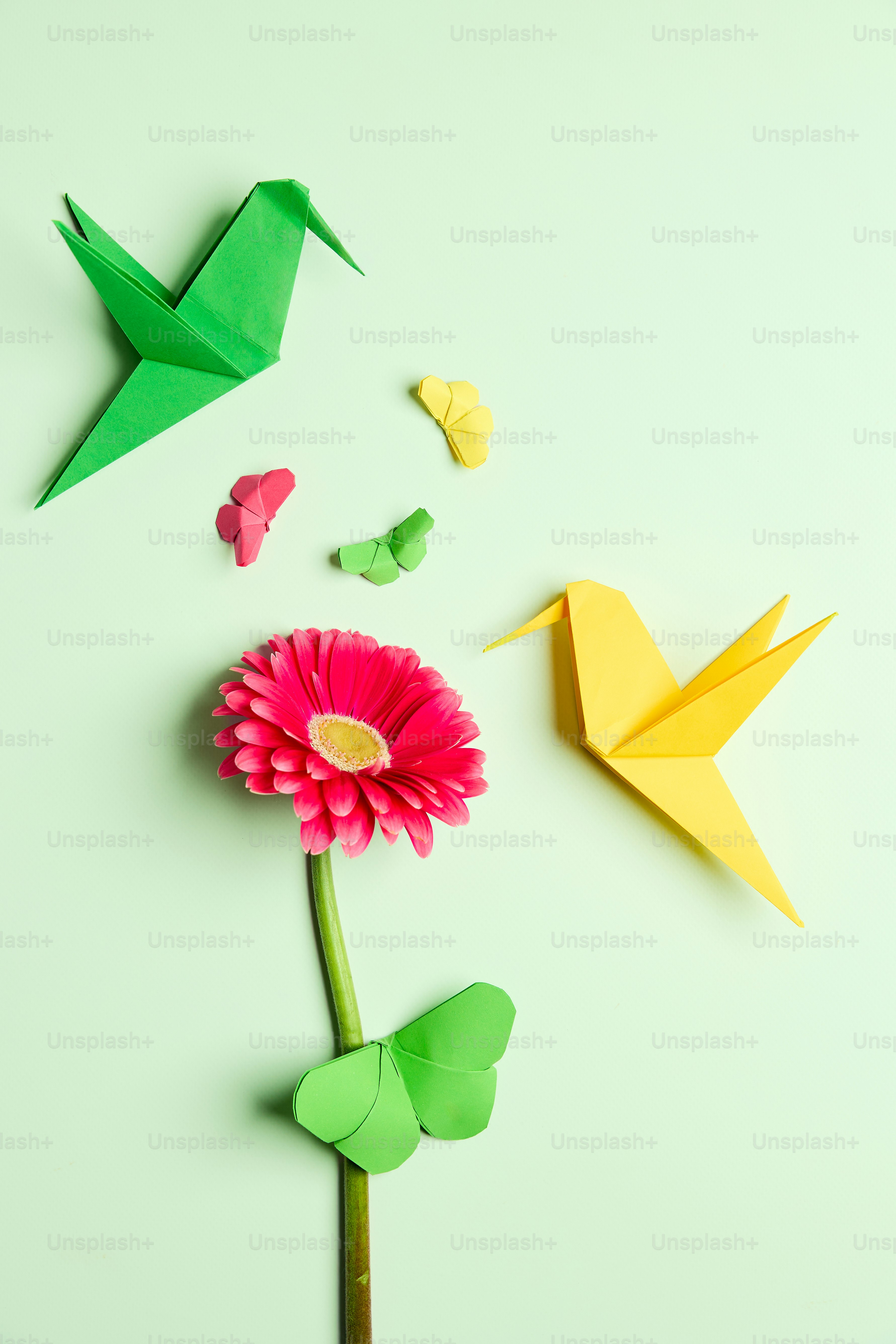 Origami birds and a flower on a green background
