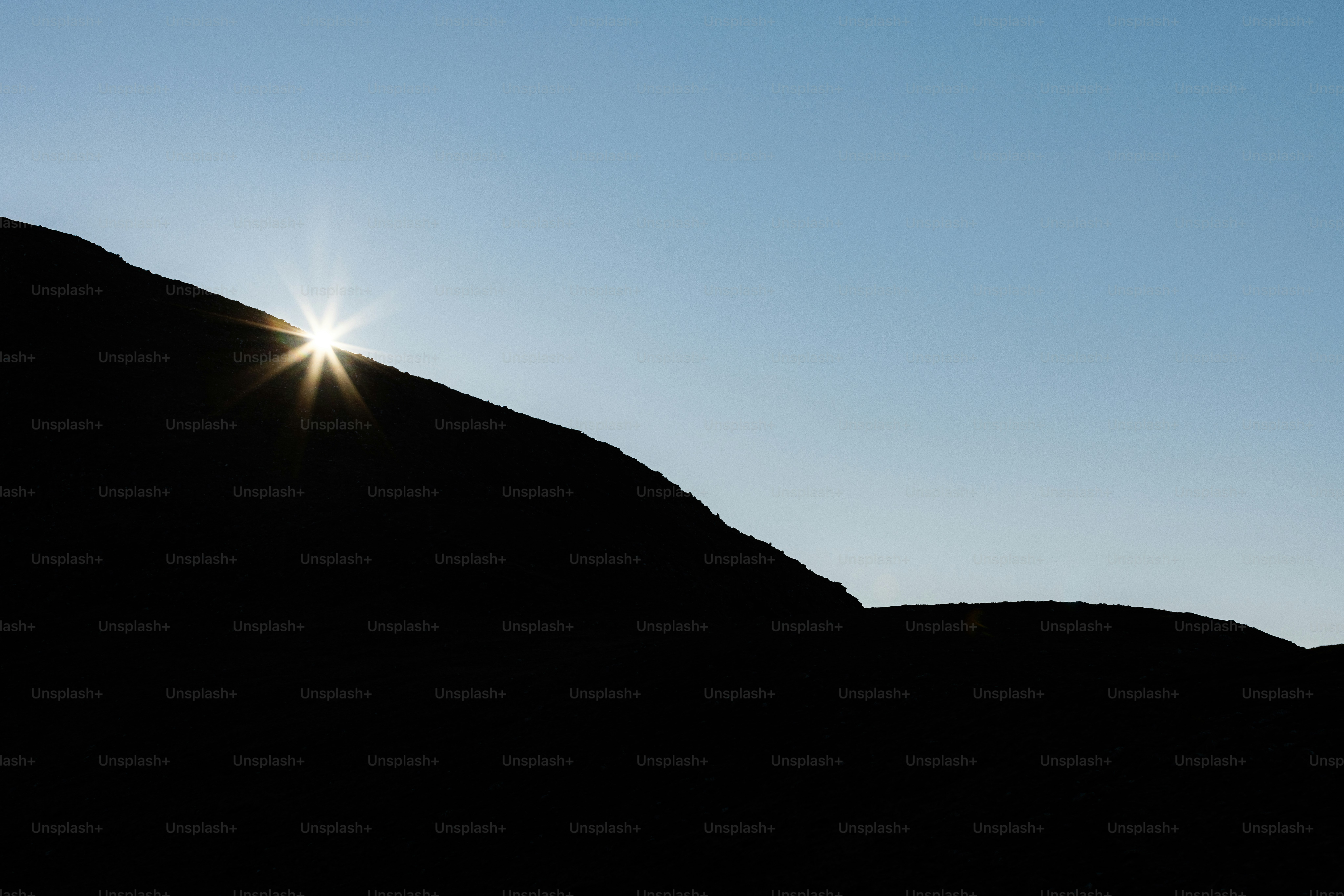 The sun shines brightly in the sky above a mountain