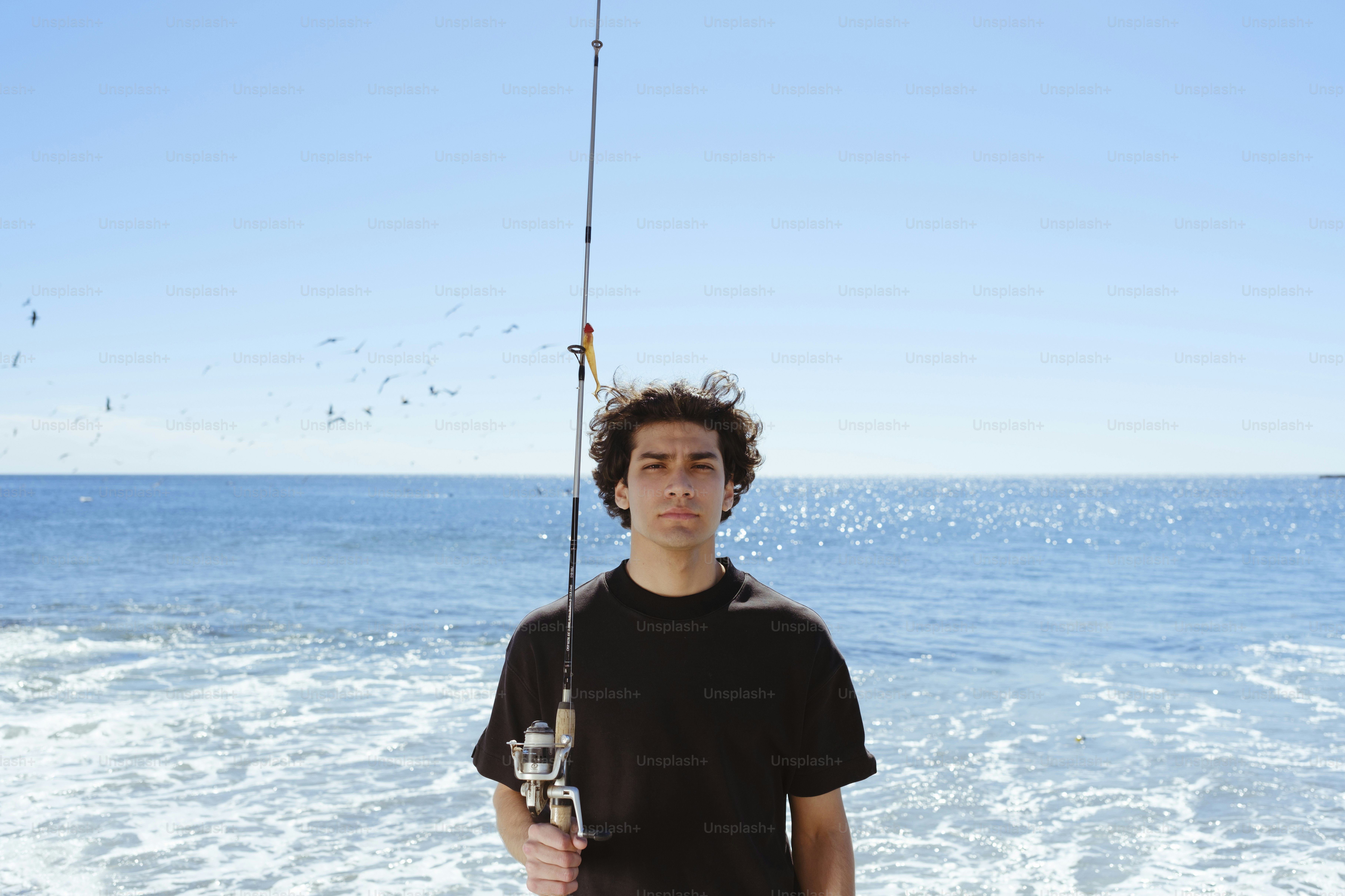 Um homem em pé em uma praia segurando uma vara de pescar