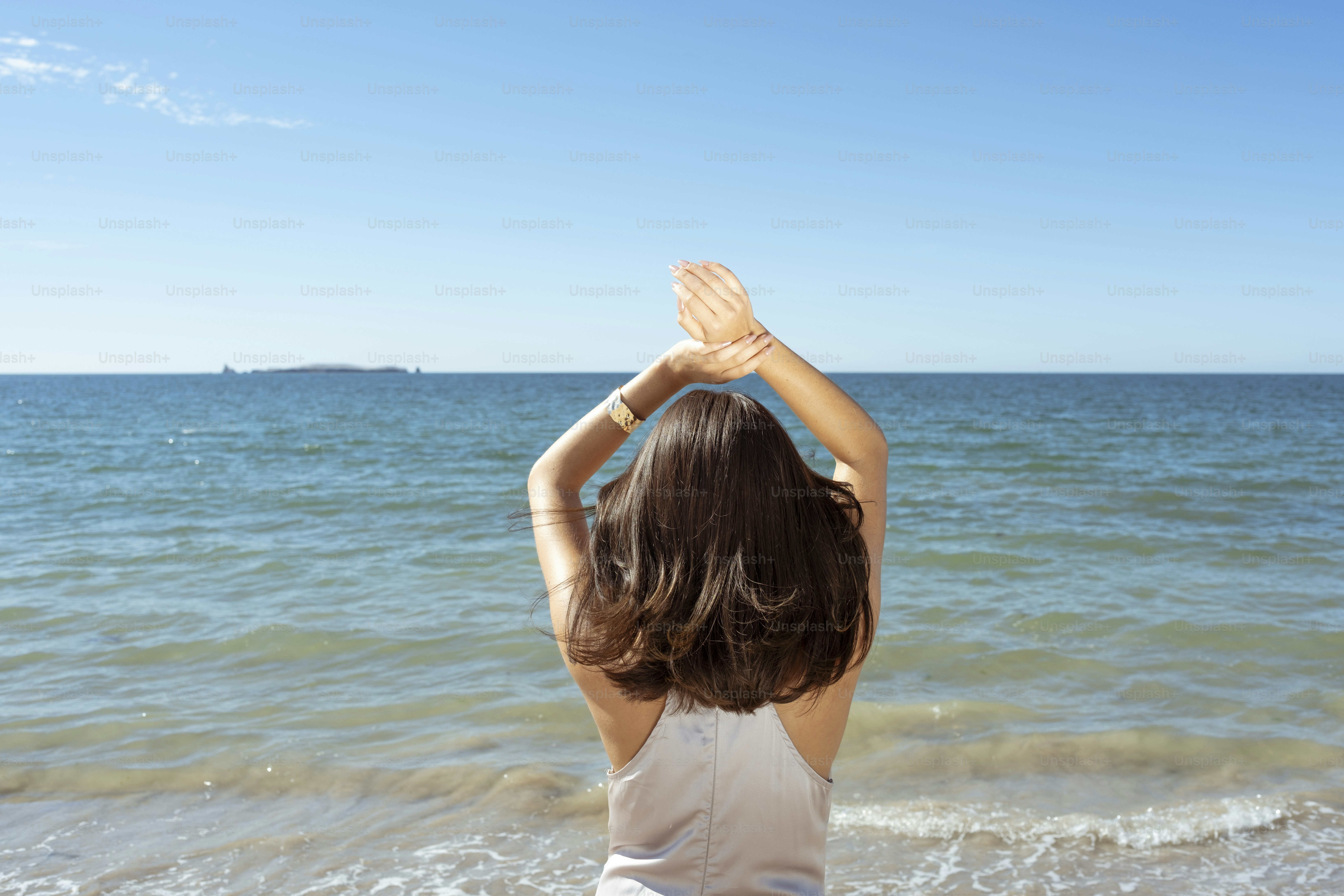 Ein kleines Mädchen steht an einem Strand am Meer
