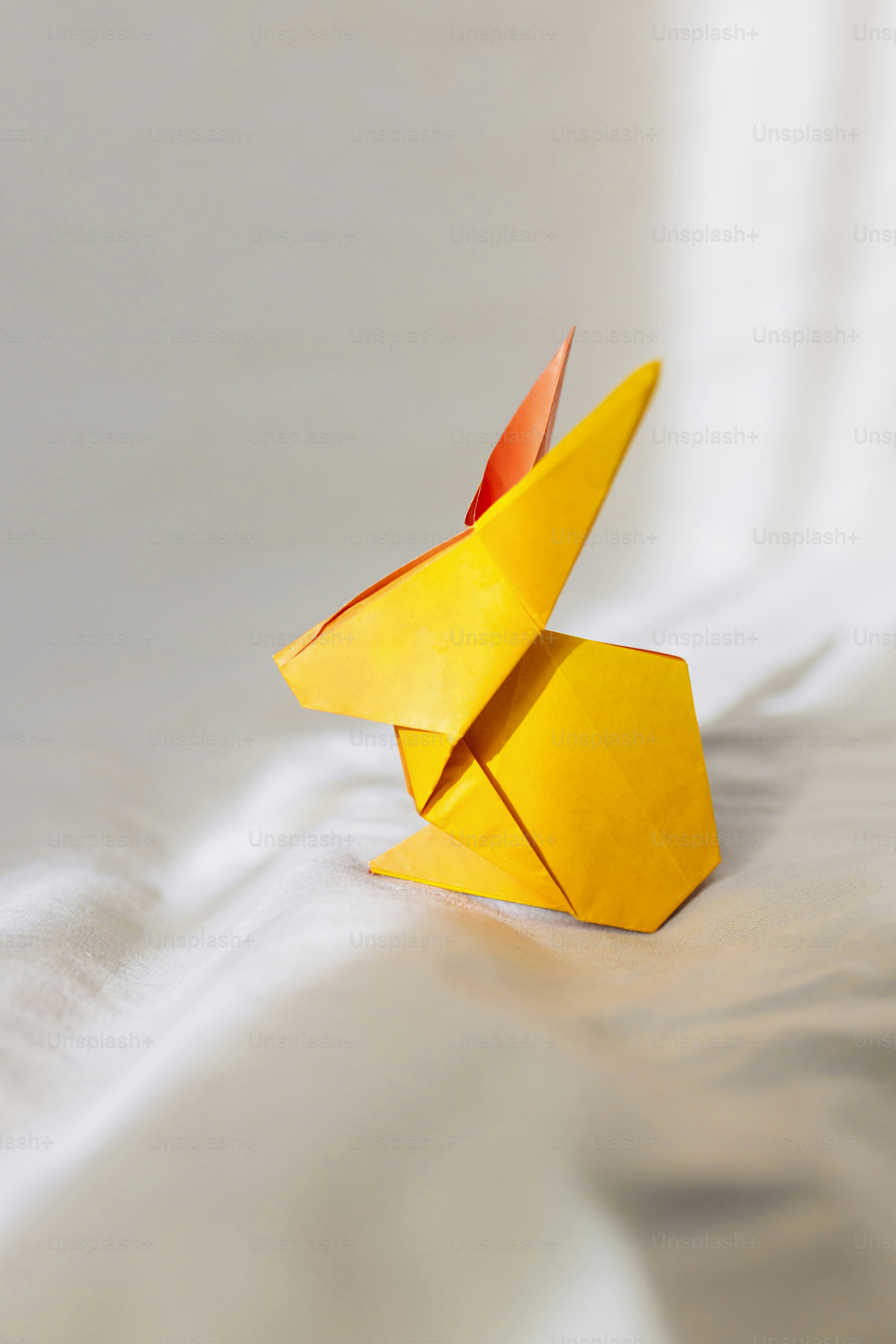 A yellow origami bird sitting on top of a bed