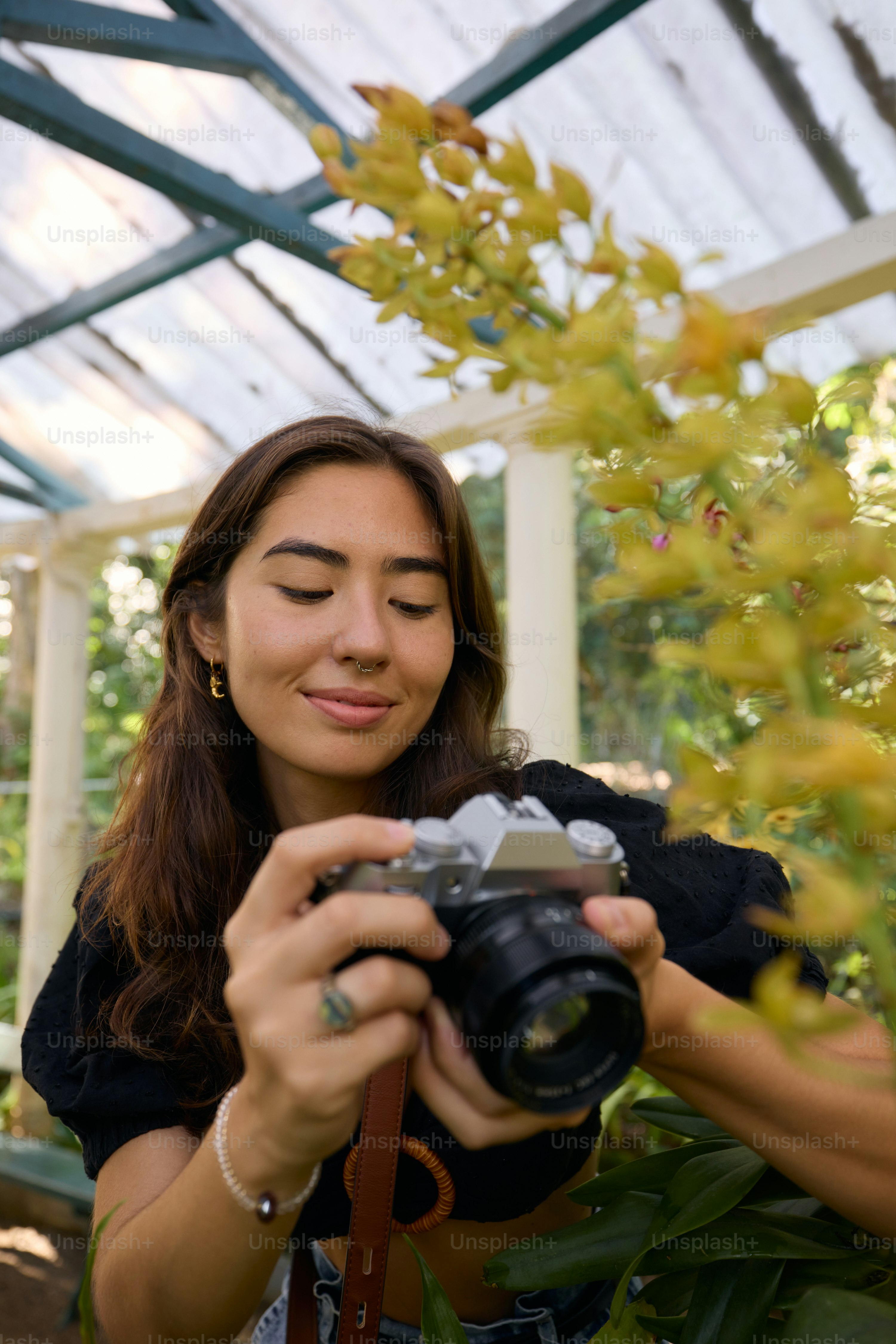 A woman holding a camera in a greenhouse