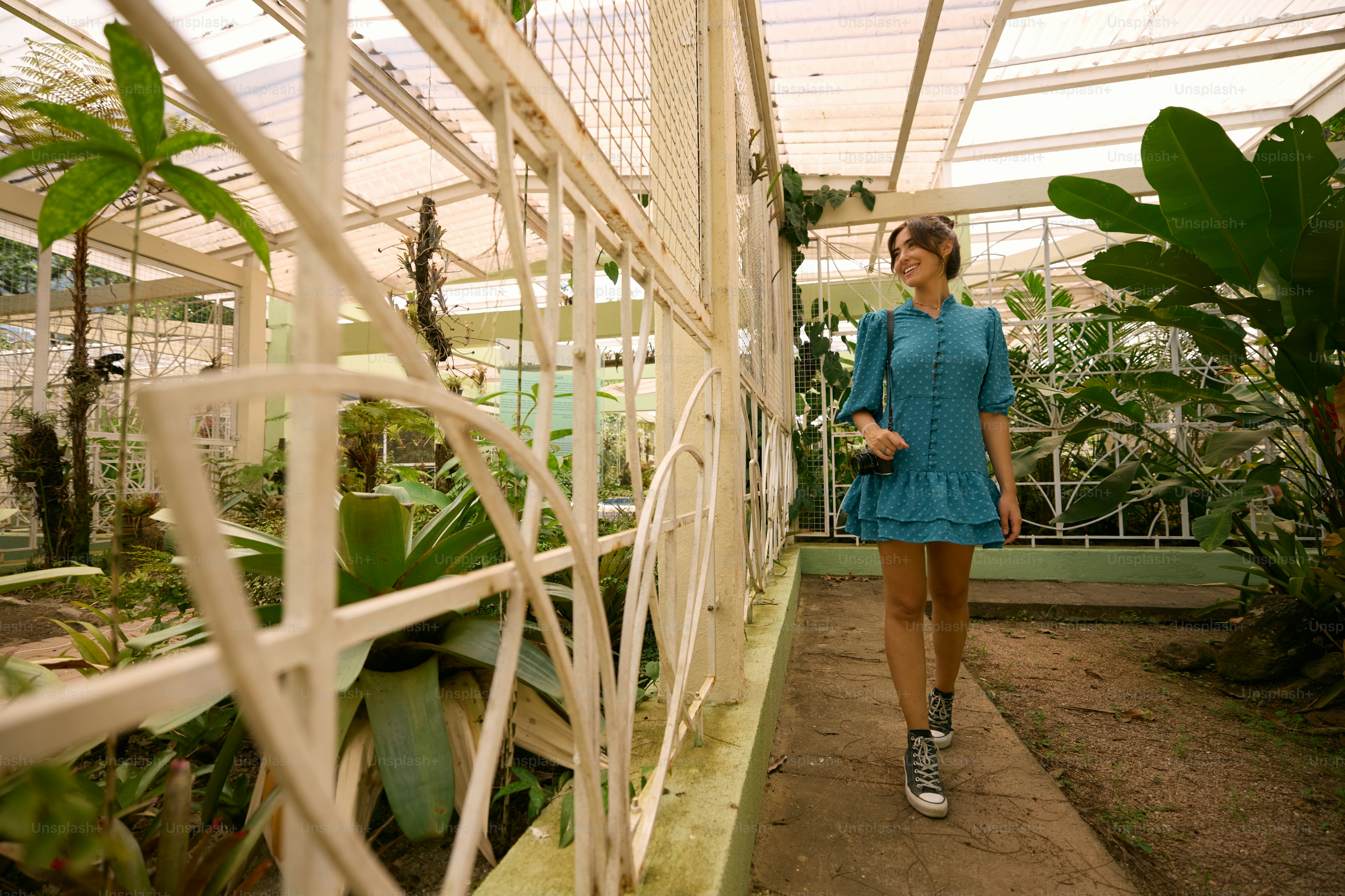 A woman in a blue dress walking through a greenhouse