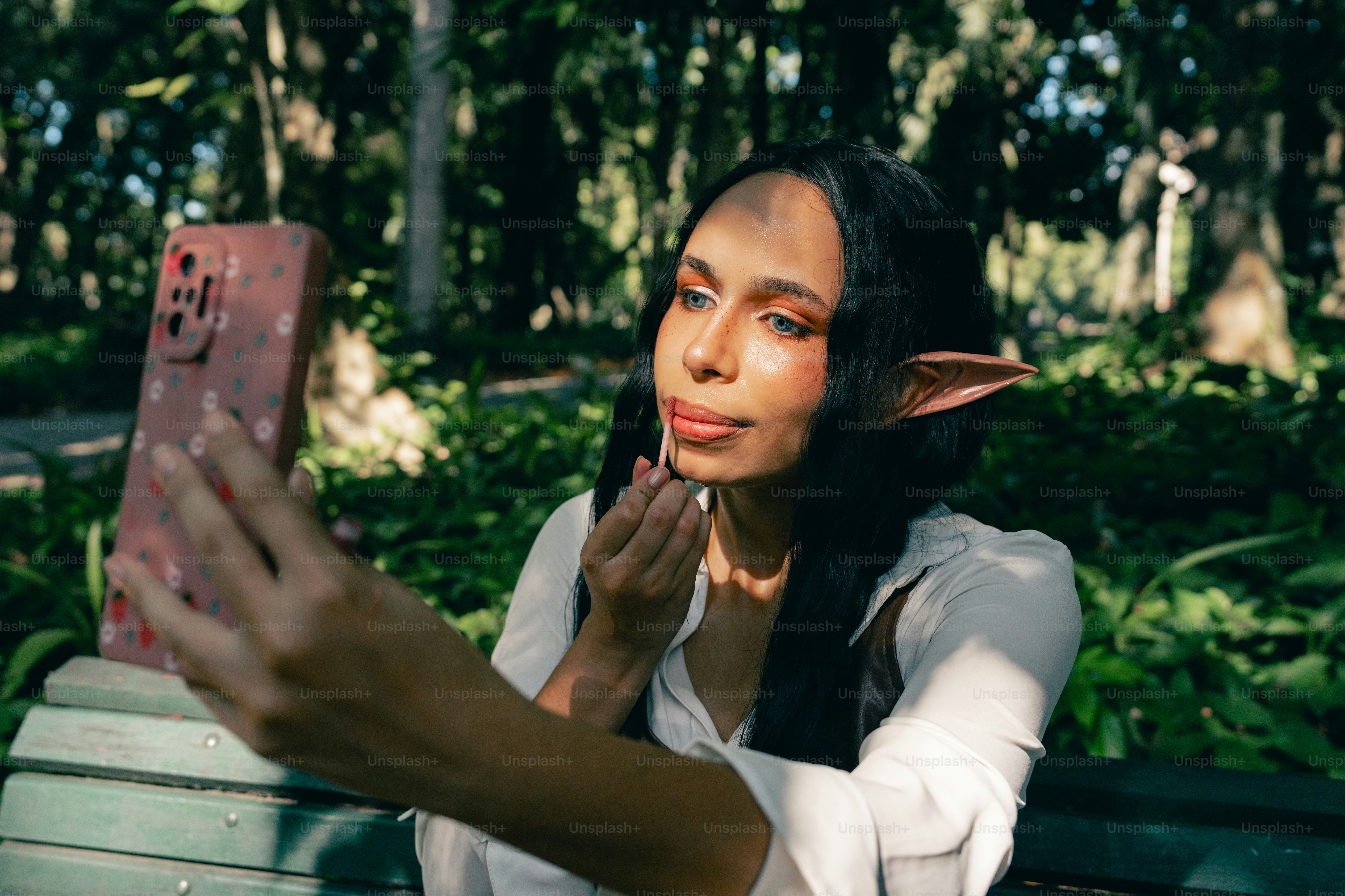 Seorang wanita duduk di bangku sambil memegang ponsel