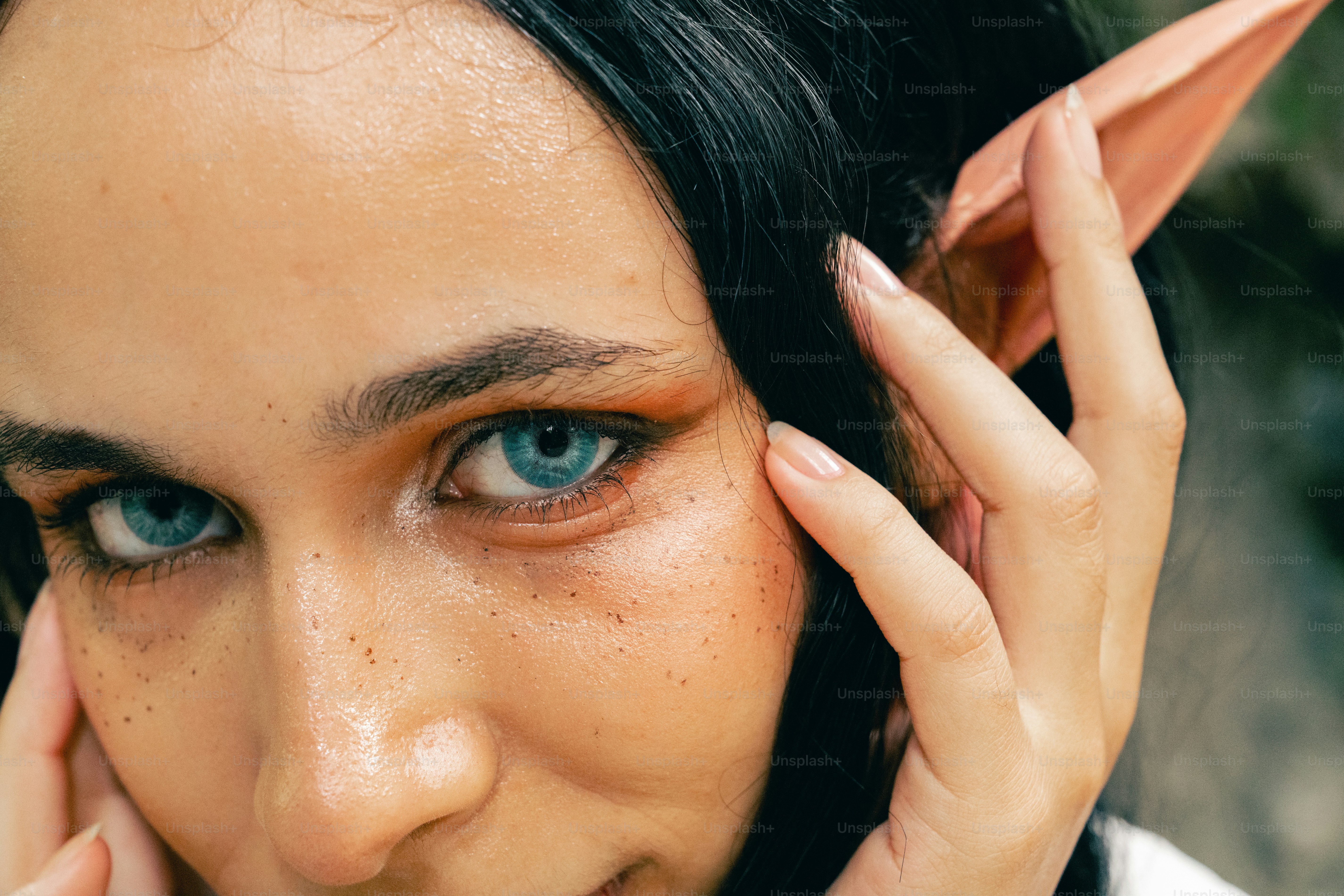 Una donna con gli occhi azzurri che si tiene la mano all'orecchio