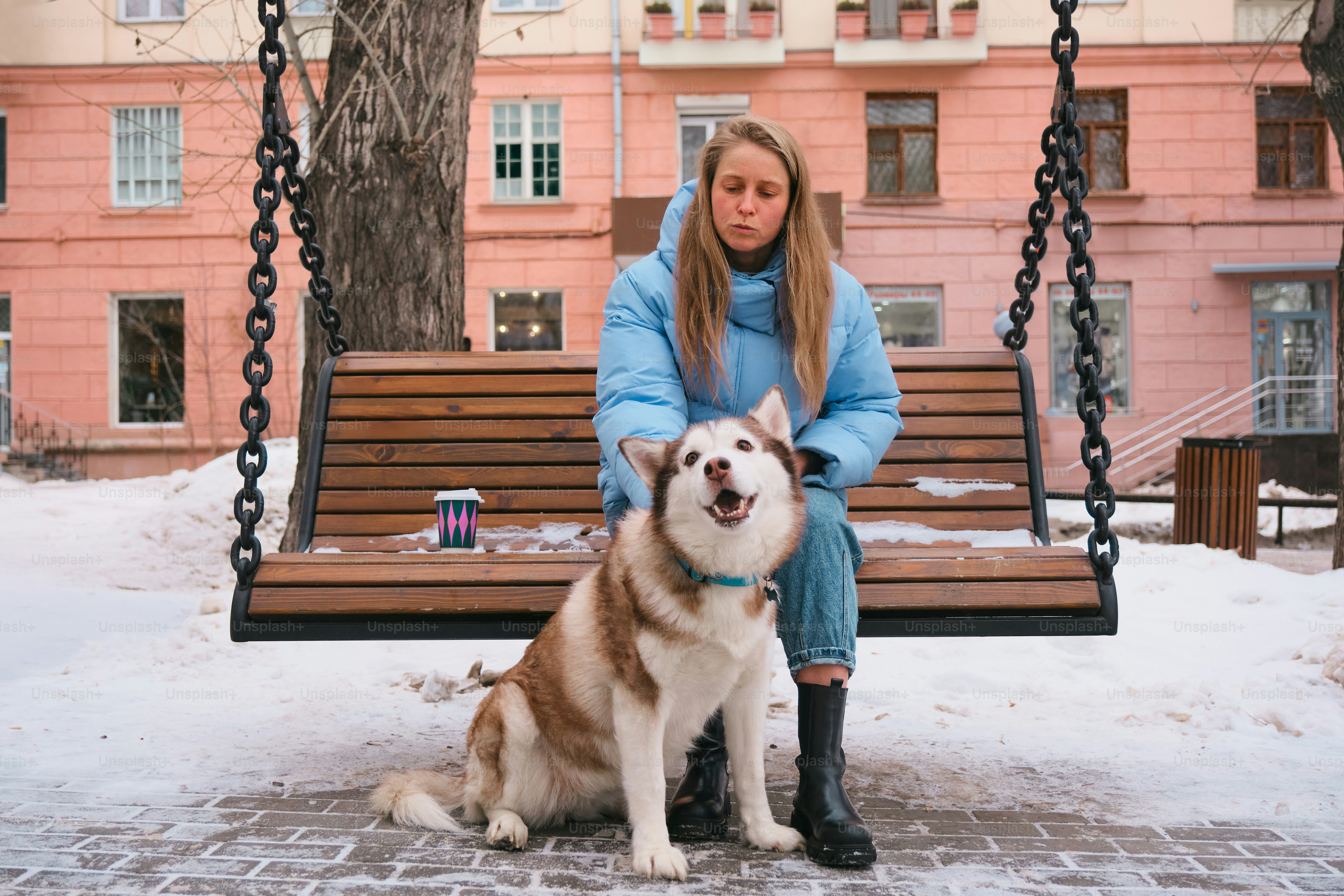 A woman sitting on a swing with a dog