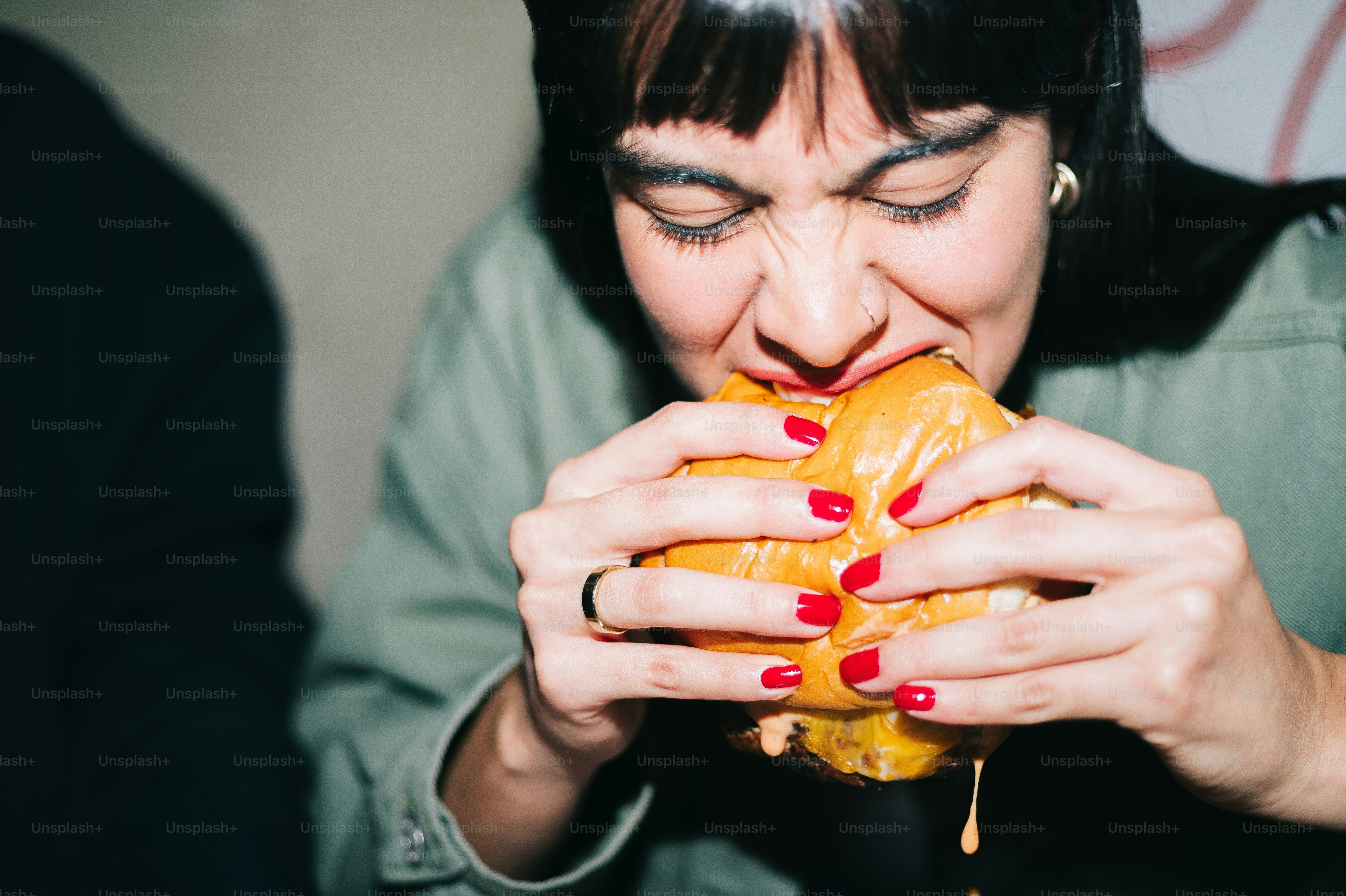 A woman is biting into a large sandwich