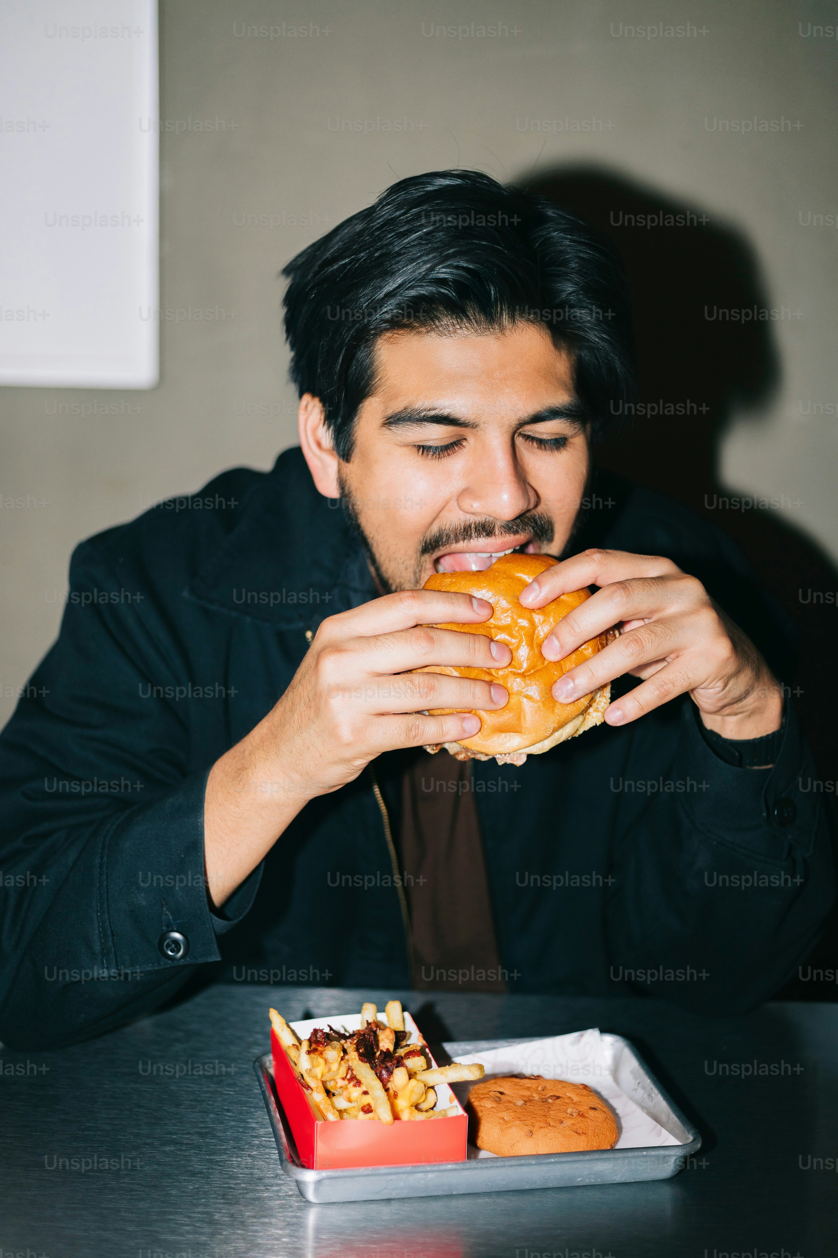 A man sitting at a table eating a doughnut