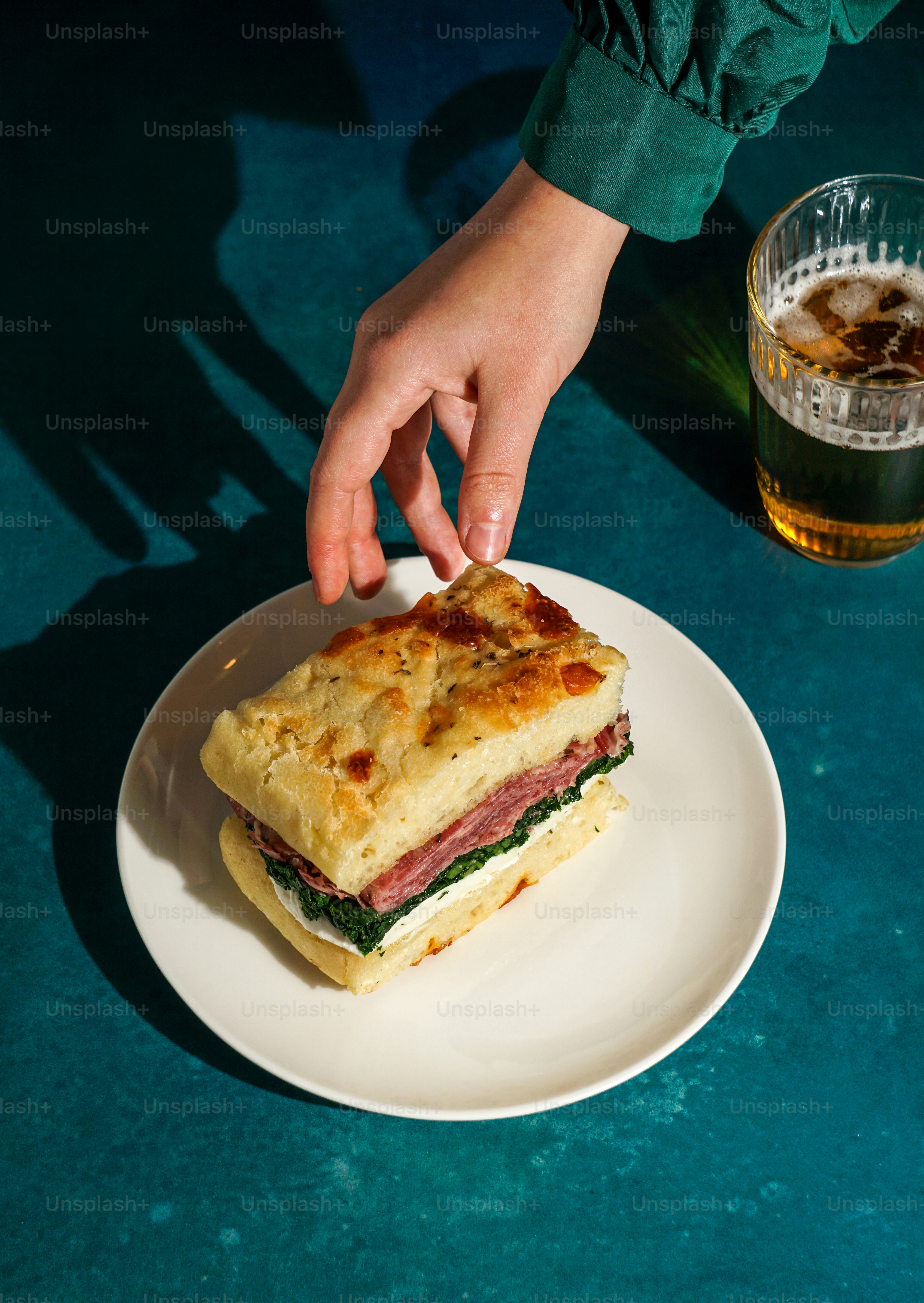 A person reaching for a sandwich on a plate
