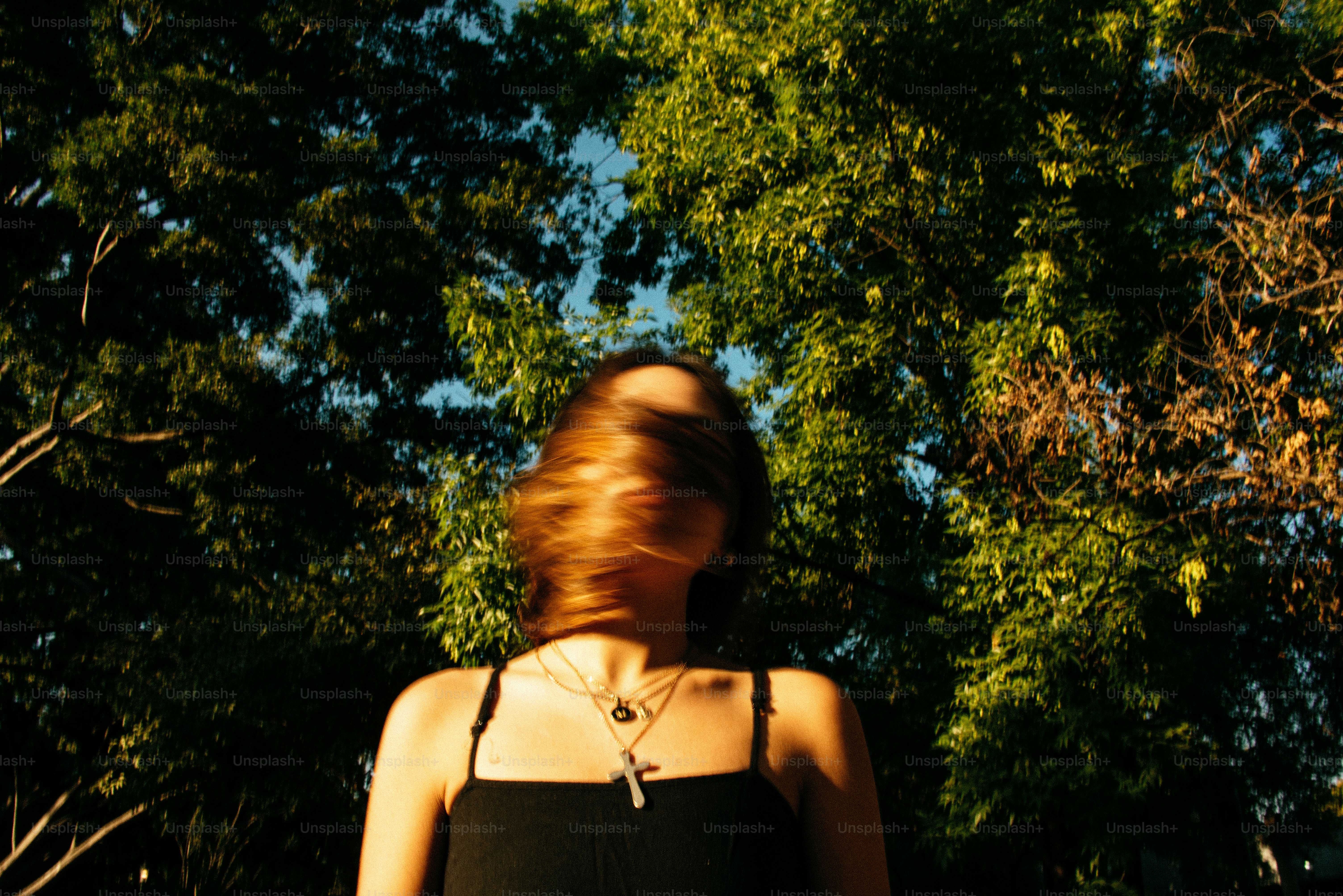 A woman in a black dress standing in front of trees photo – Motion ...