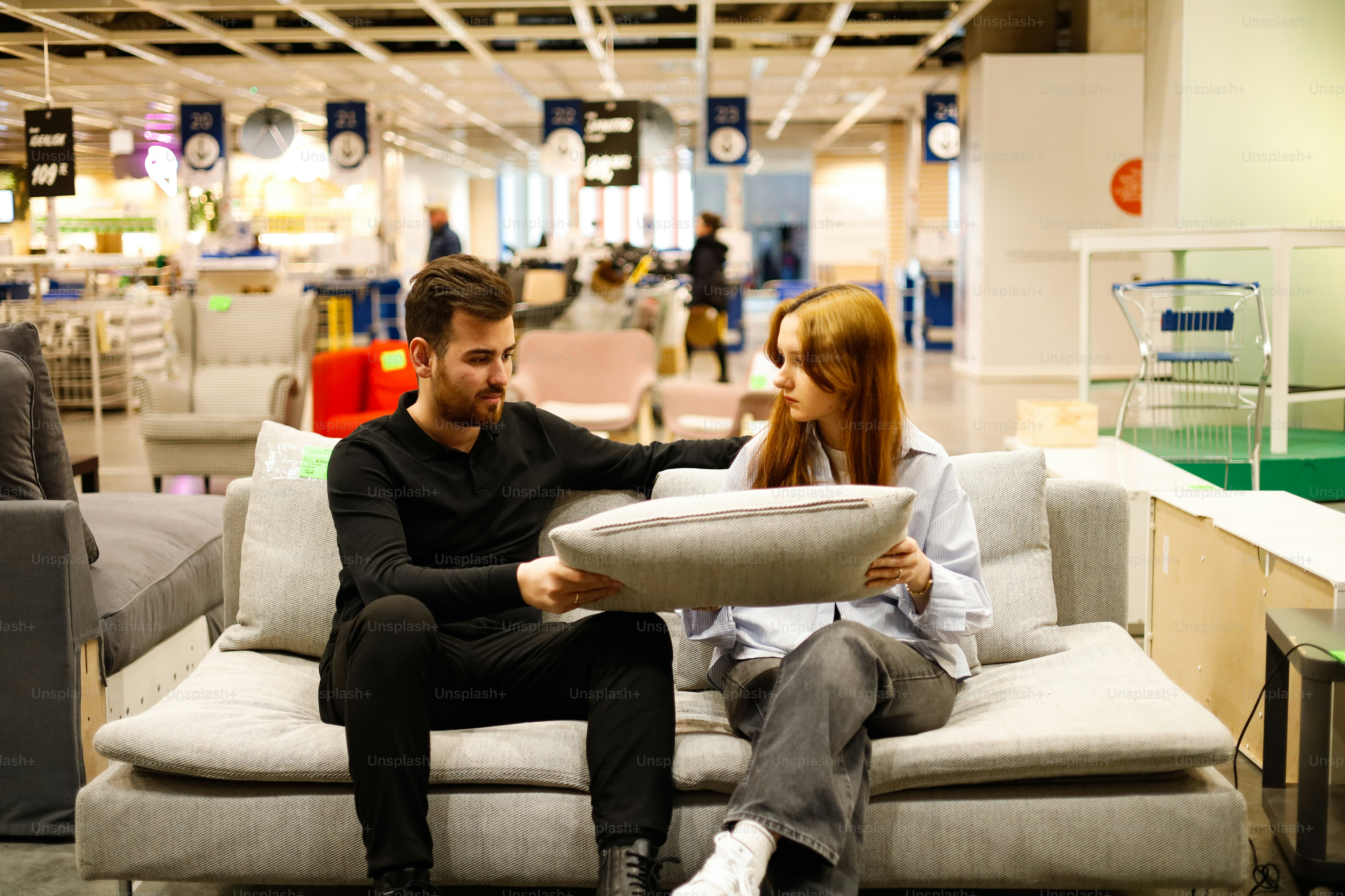 A man and a woman sitting on a couch in a store