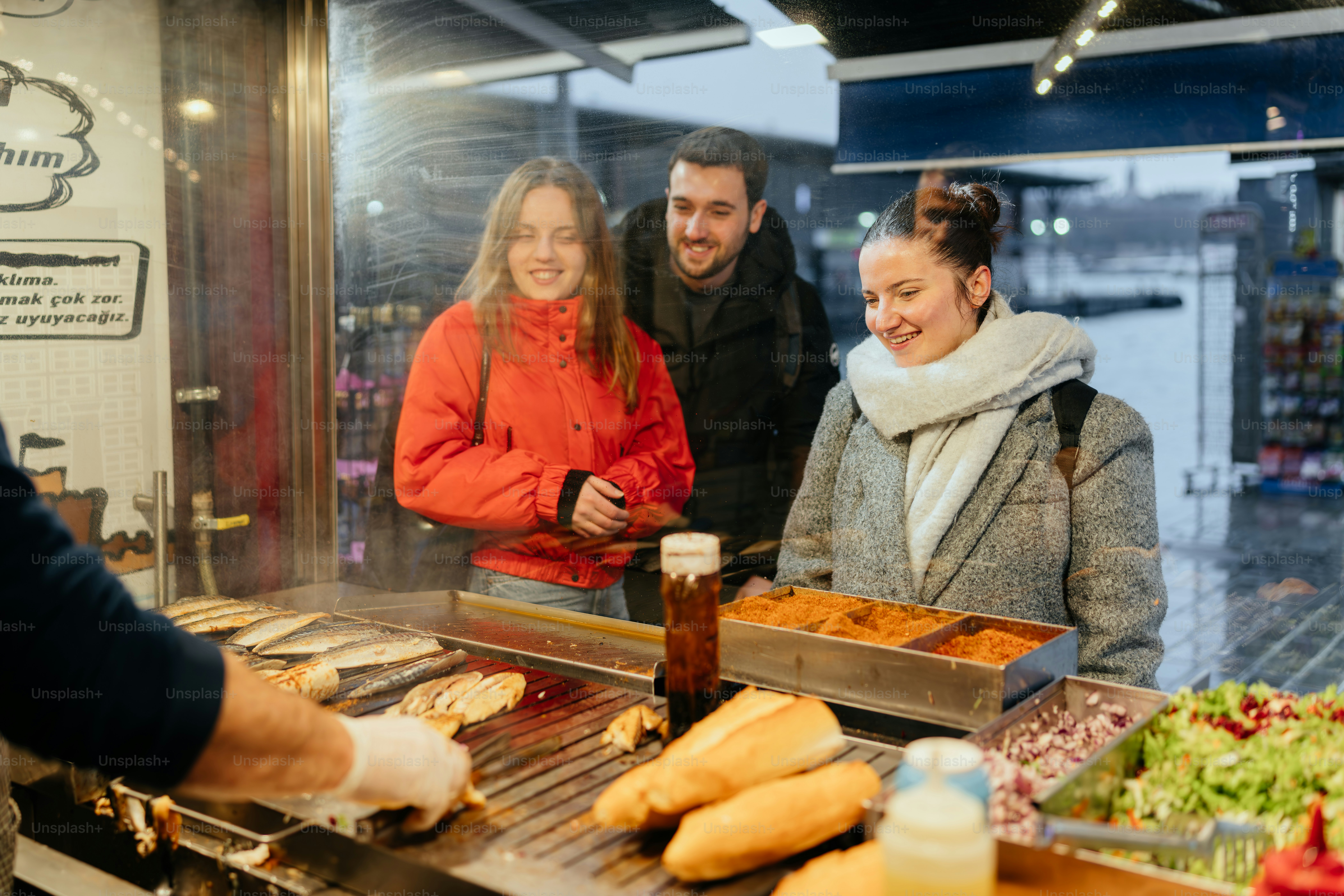 A group of people standing around a counter filled with food