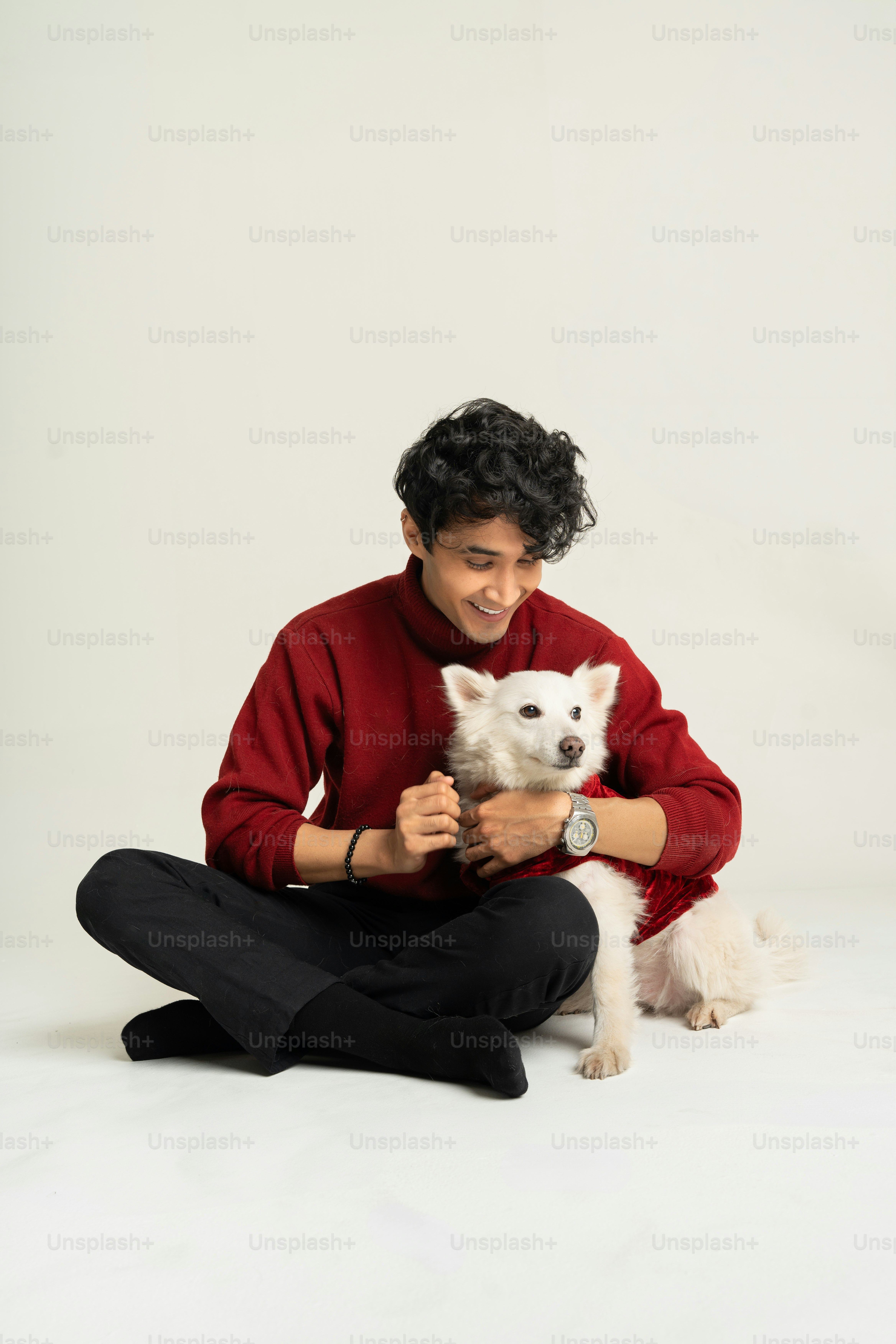 A man sitting on the floor holding a white dog