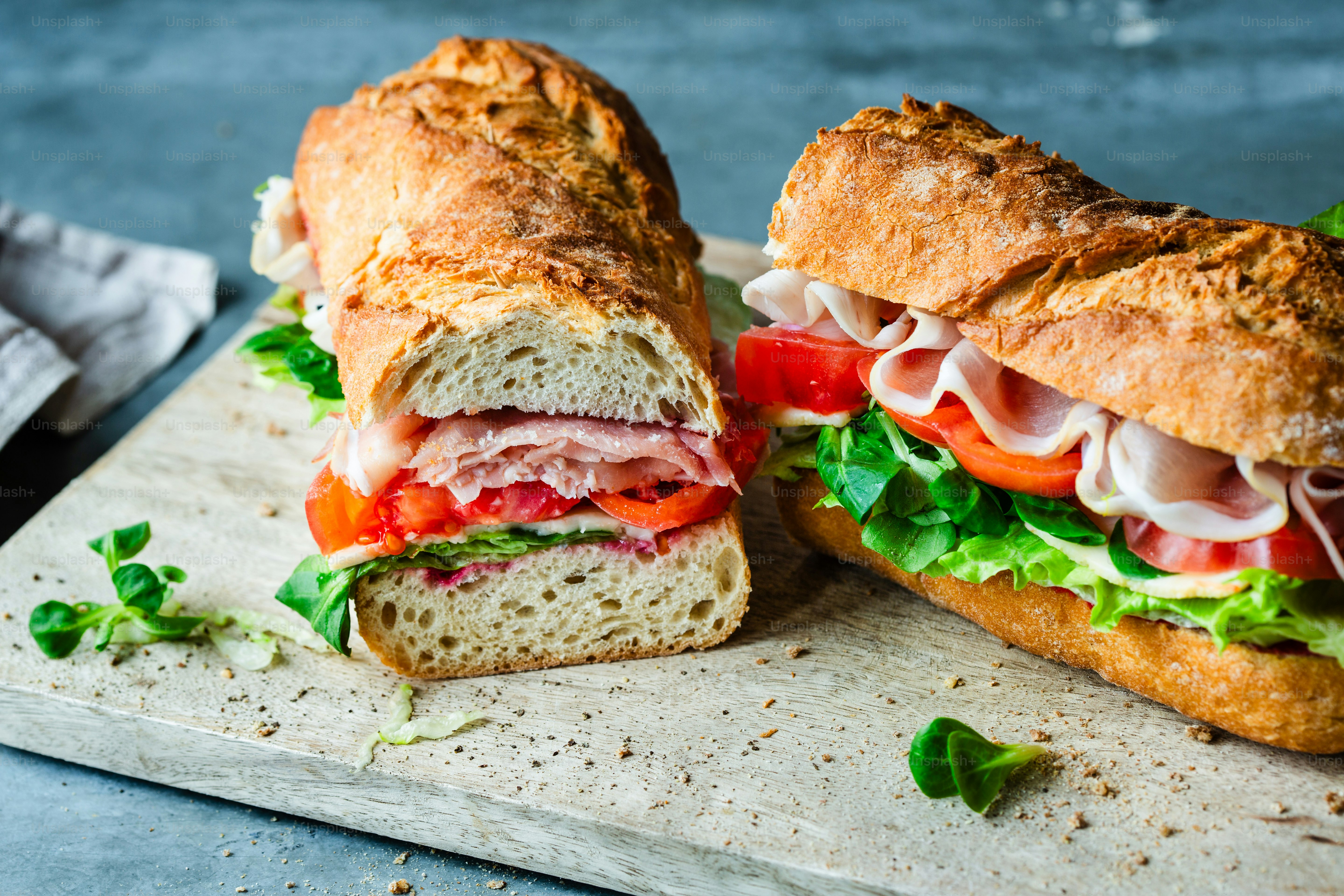 A sandwich cut in half sitting on top of a cutting board