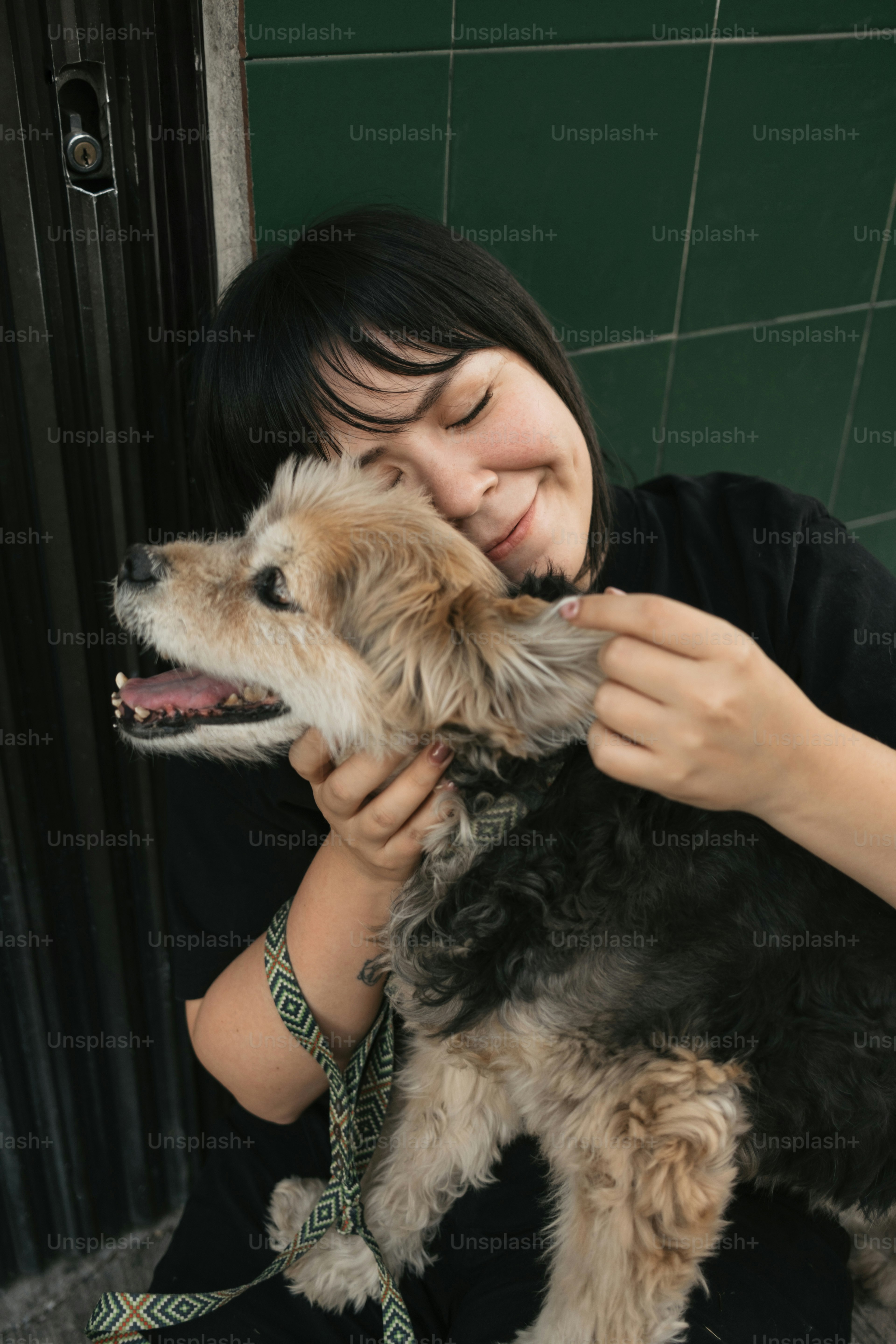 A woman is petting a small dog on a leash
