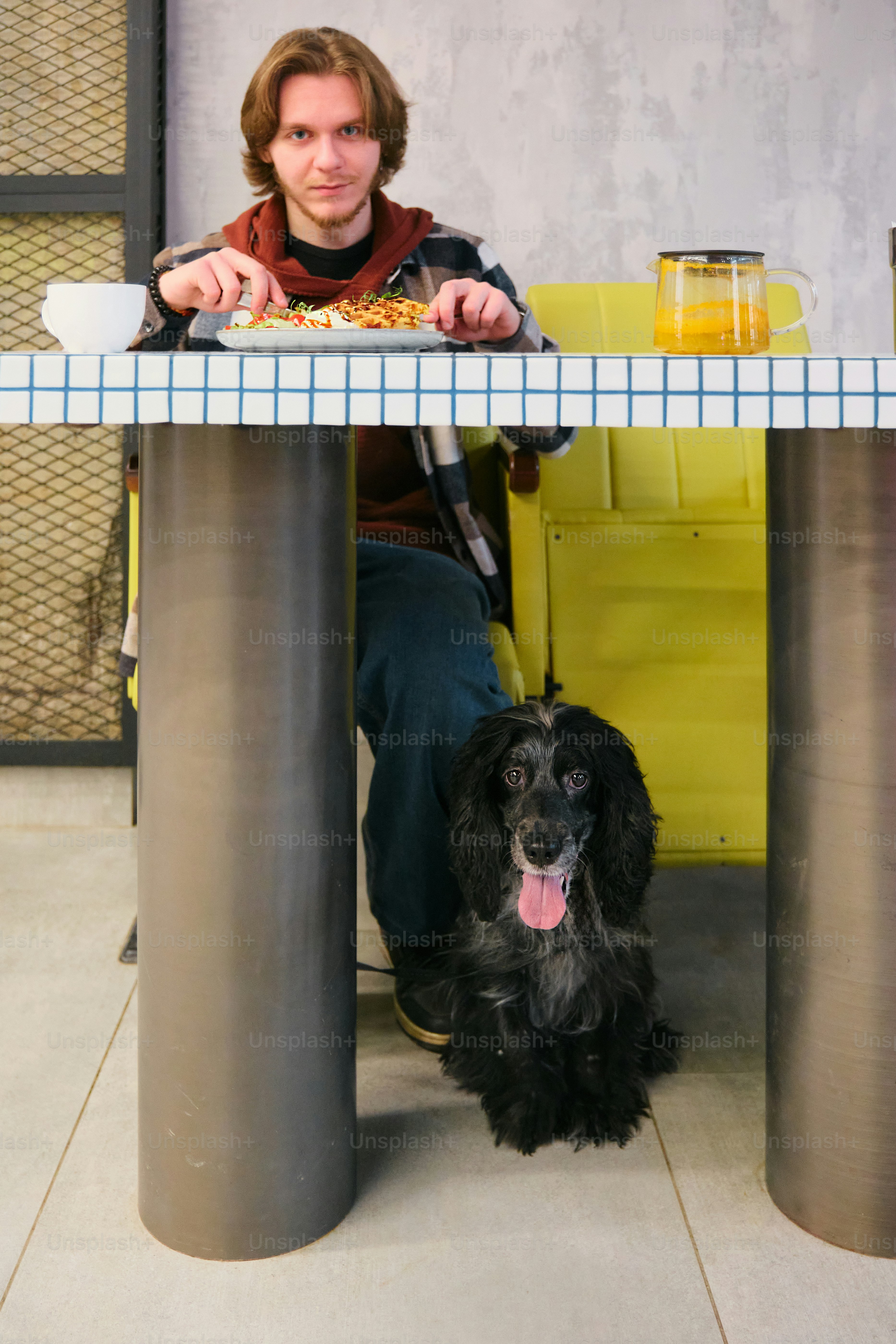 A woman sitting at a table with a black dog