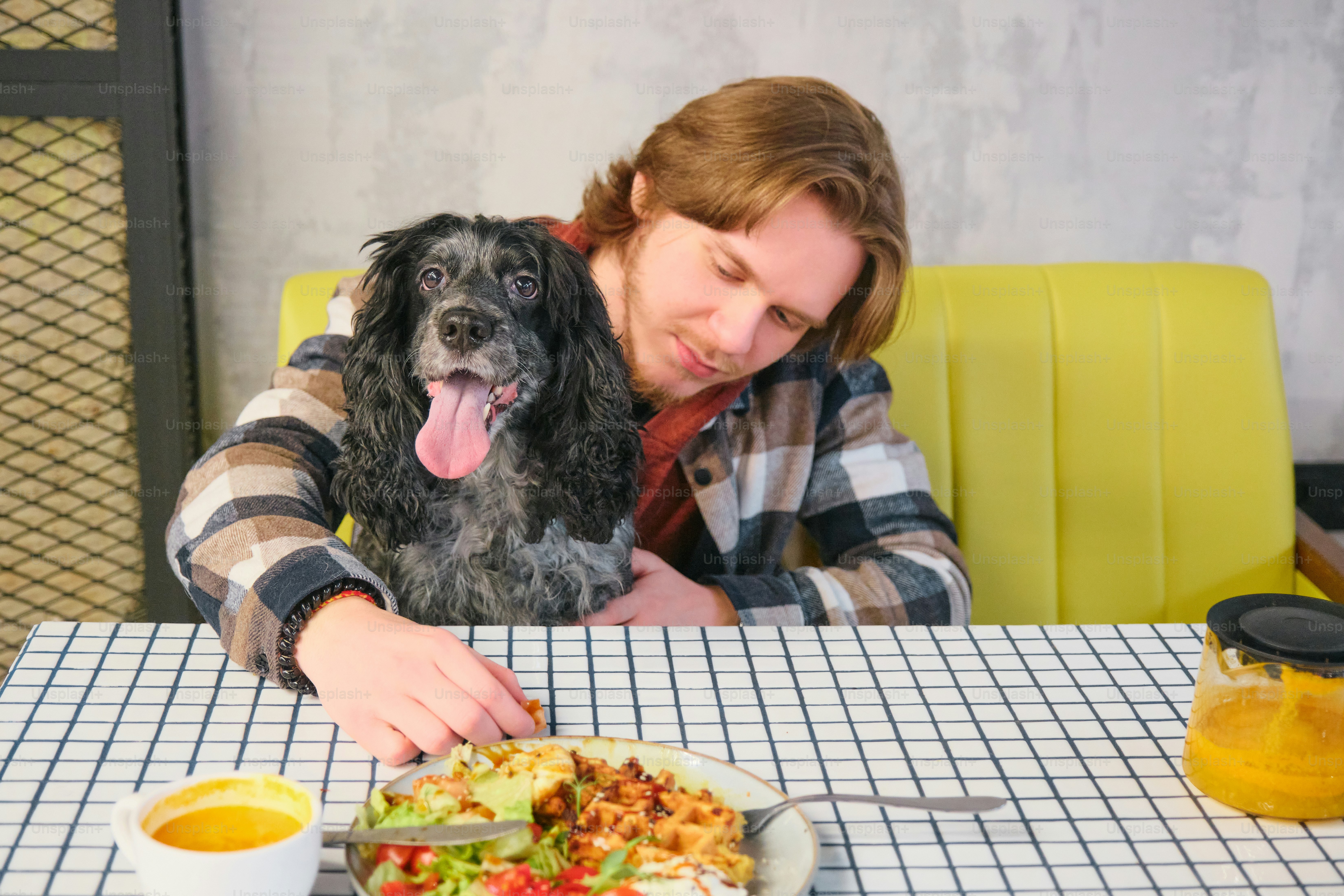 A woman sitting at a table with a dog in front of her