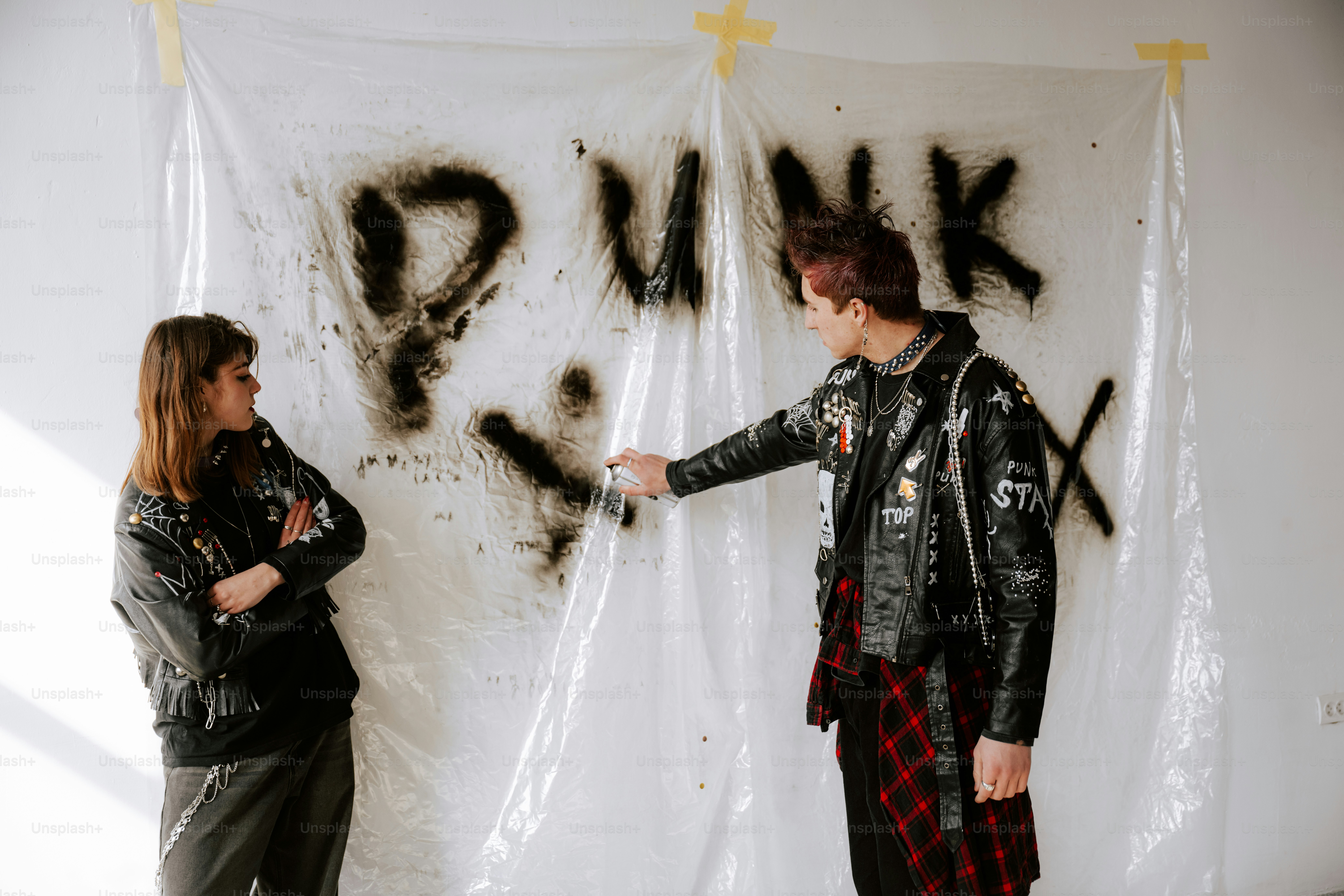 Dos personas de pie frente a una pared cubierta de grafitis