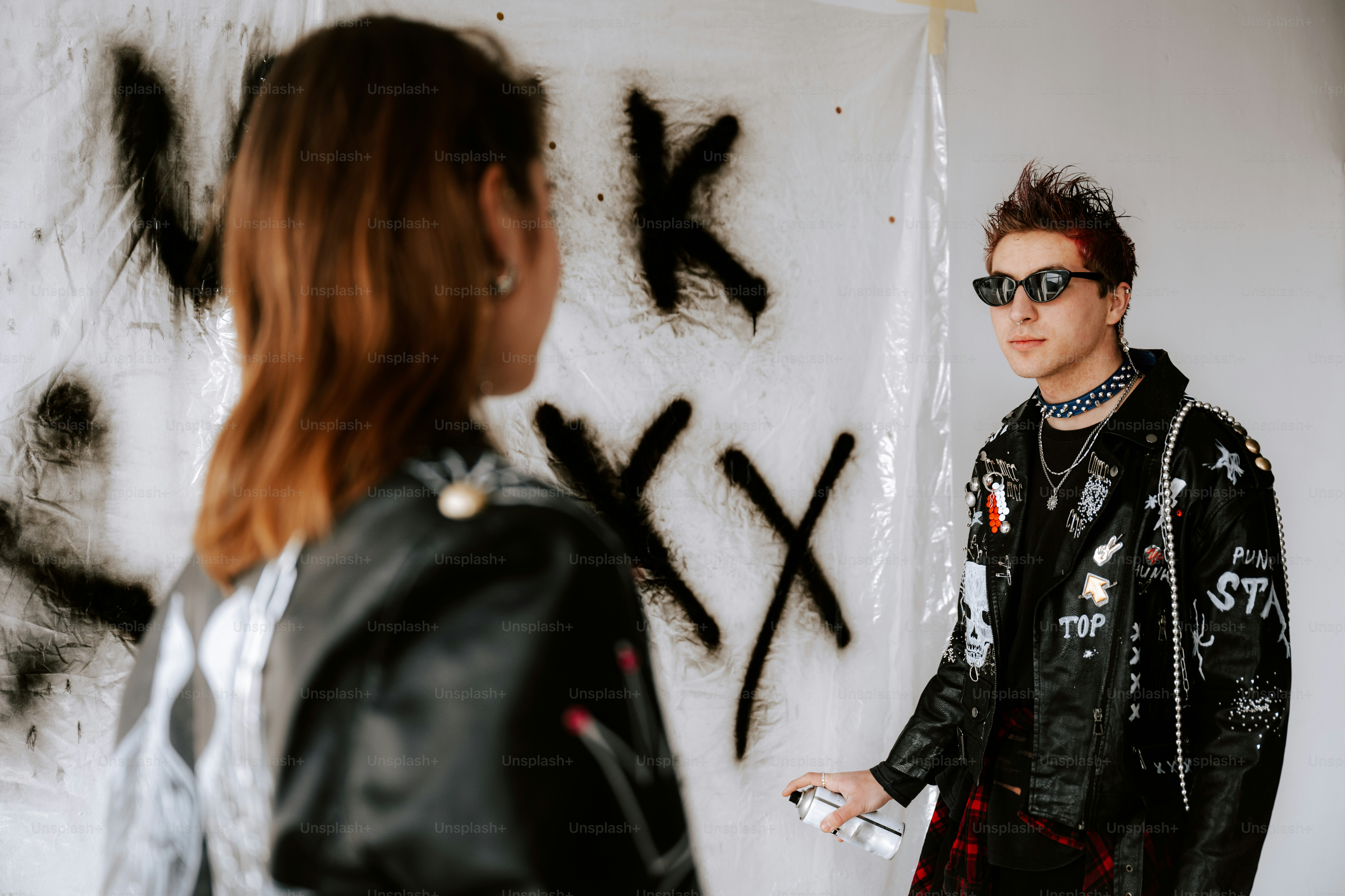 A man and a woman standing in front of a wall with graffiti