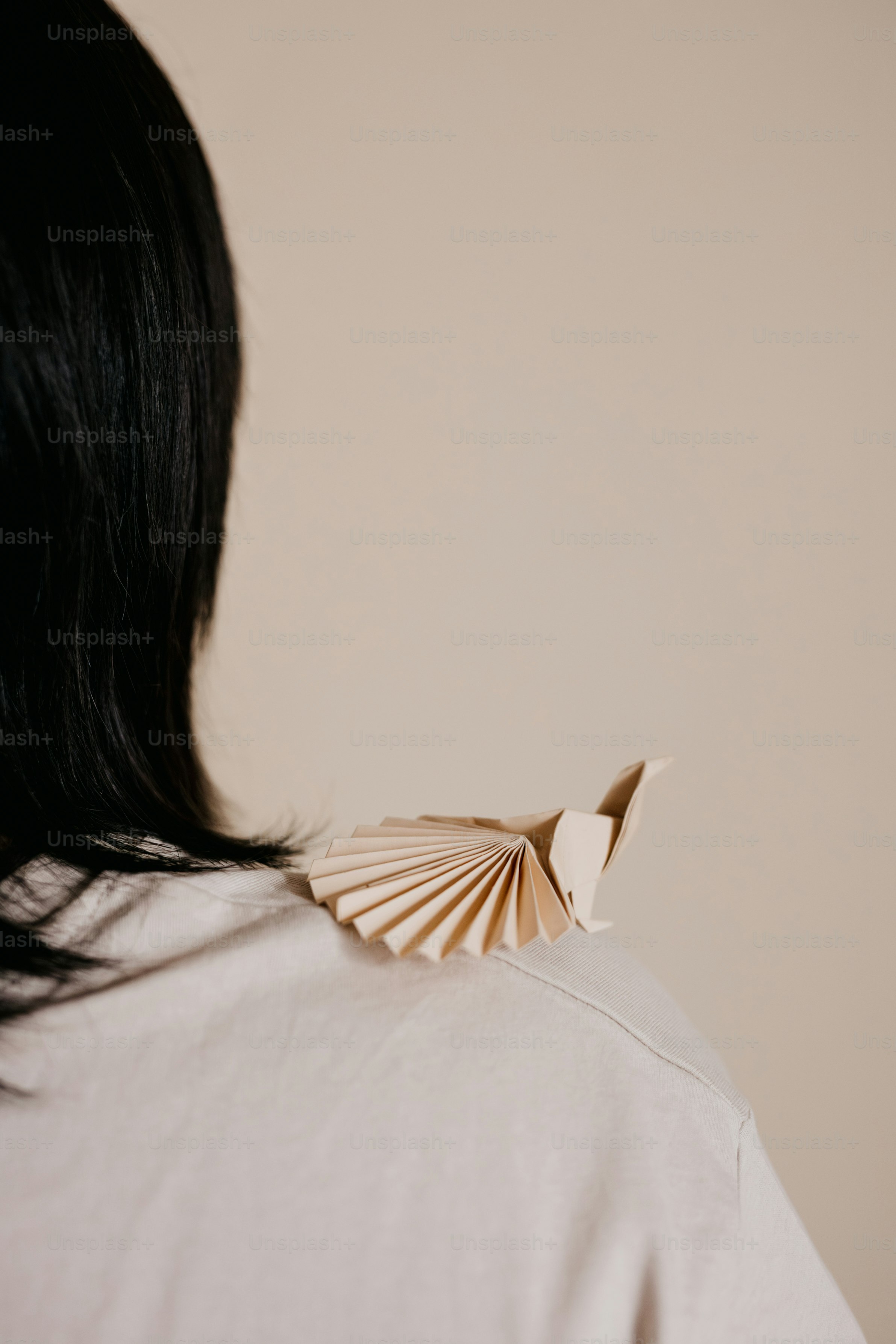 The back of a woman's head with a paper bird on it