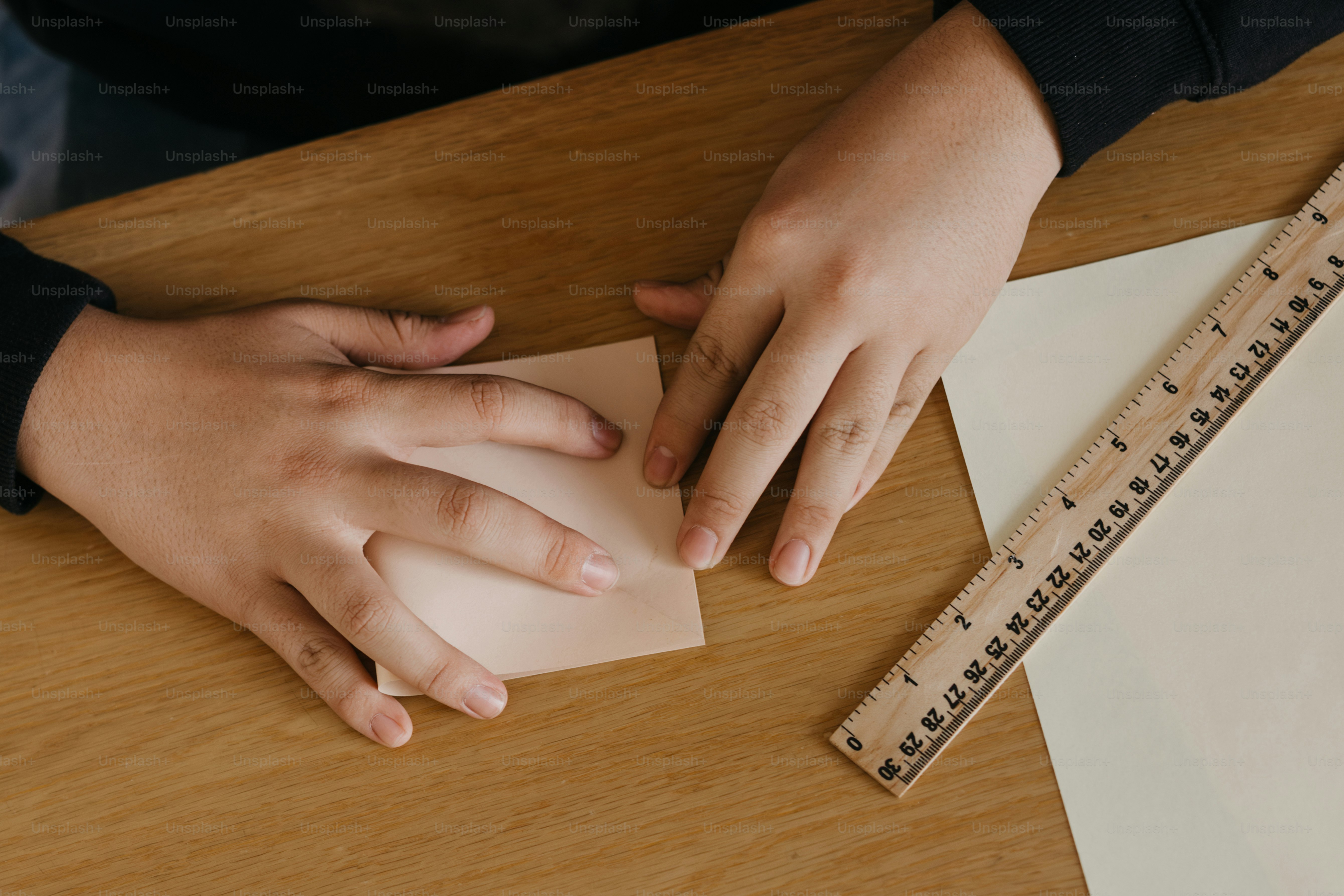 A person holding a piece of paper next to a ruler