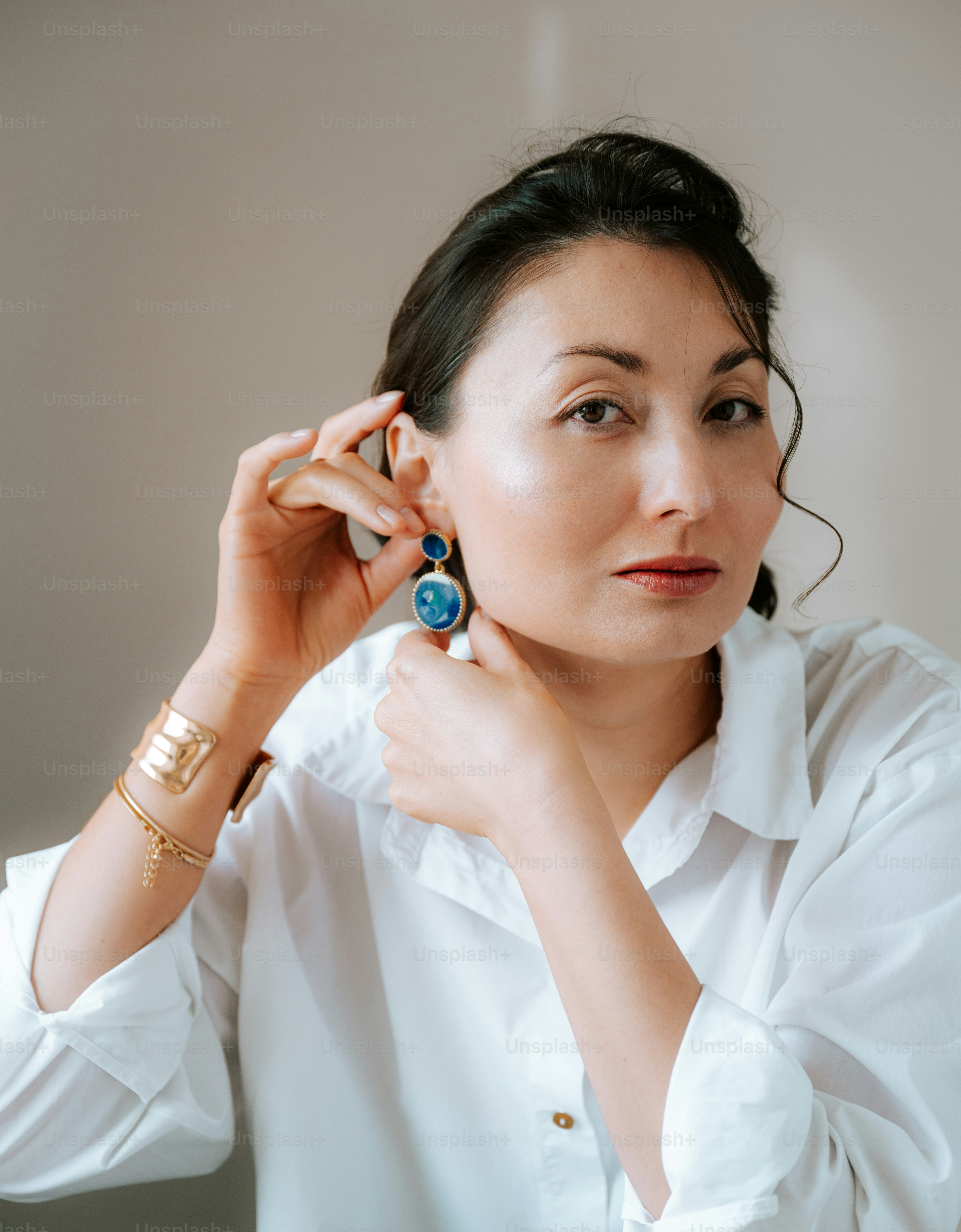 A woman in a white shirt holding a pair of earrings