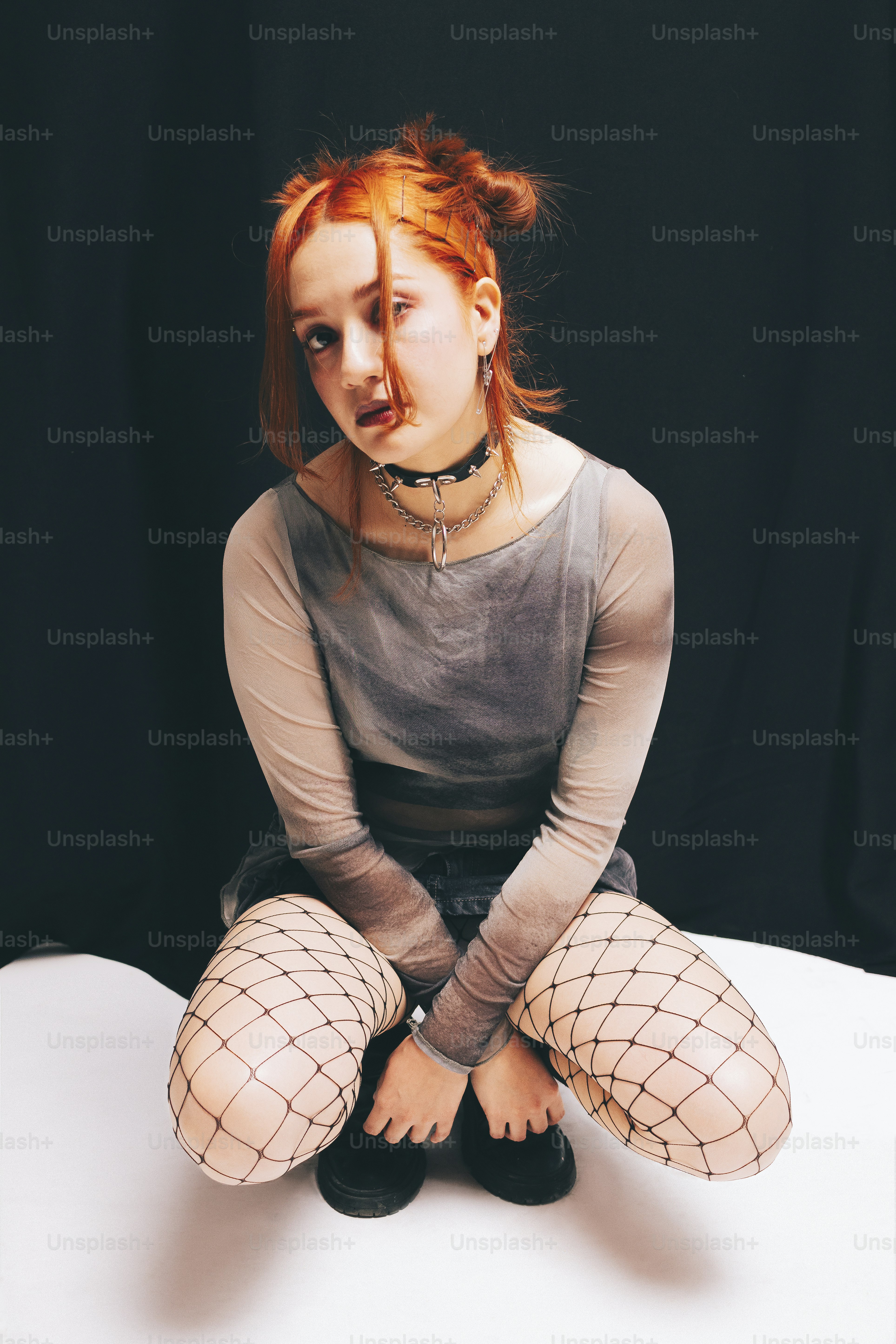 A woman with red hair sitting on a white surface