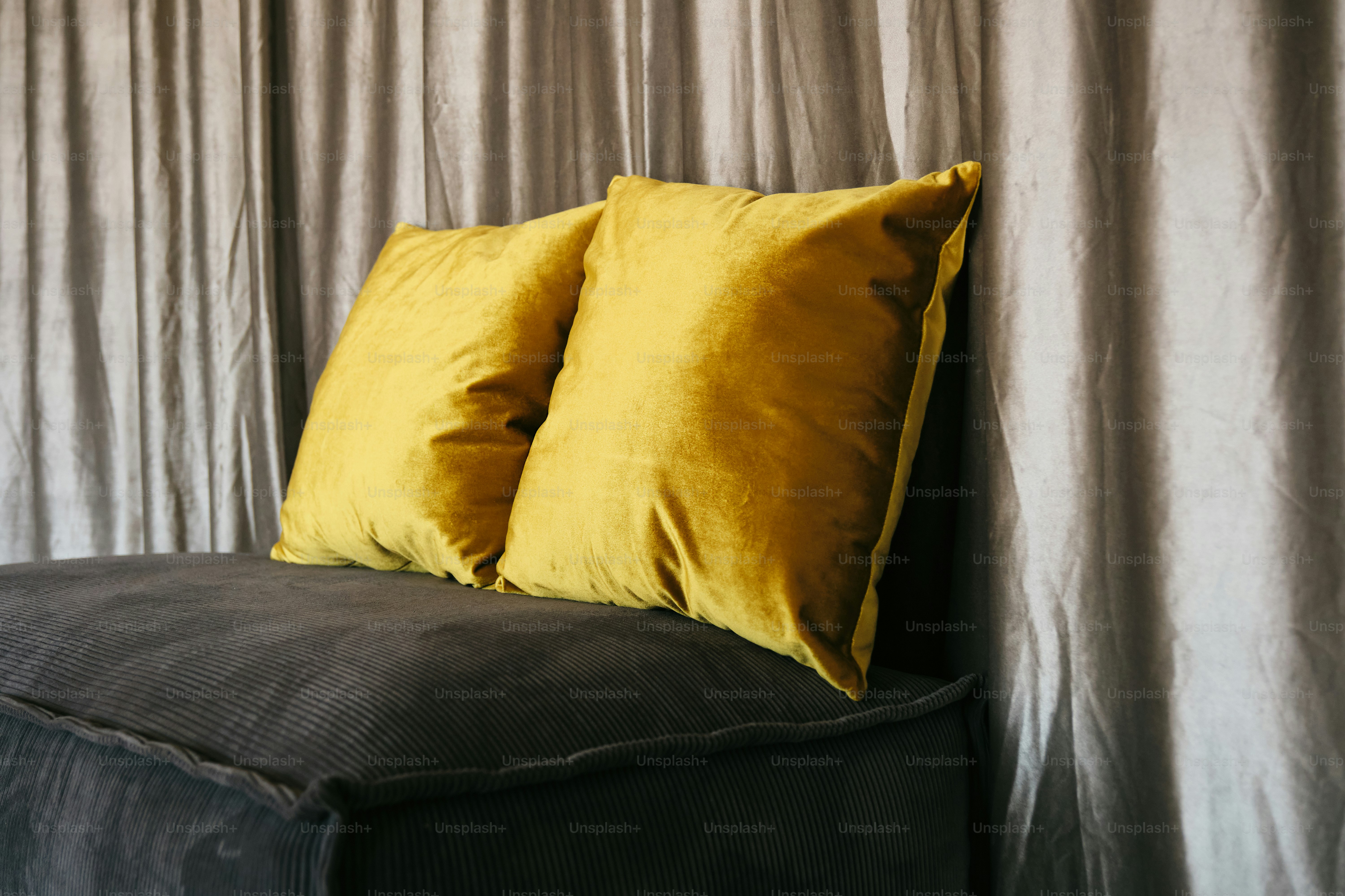A black couch with two yellow pillows on top of it