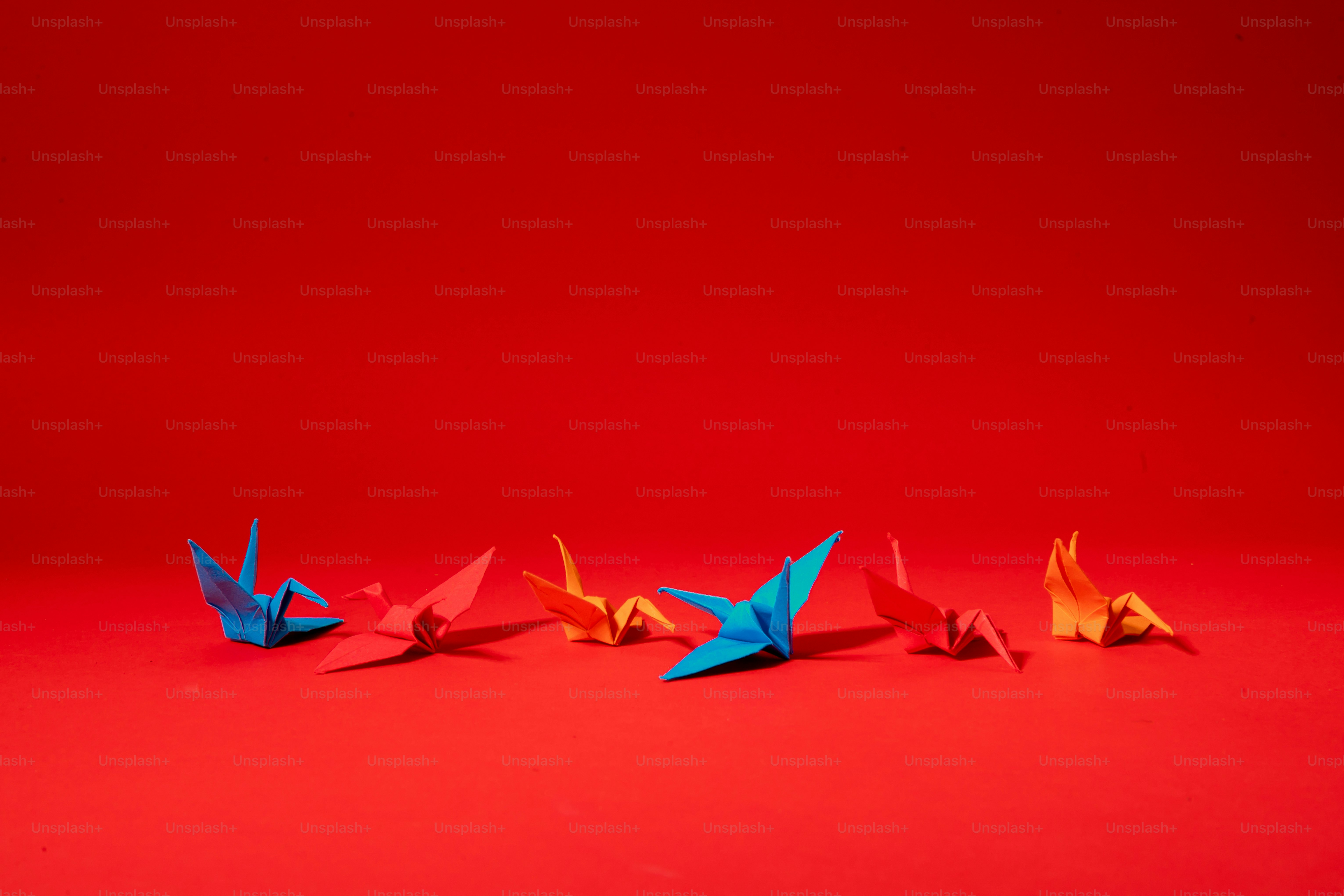Eine Gruppe von Origami-Vögeln auf rotem Hintergrund