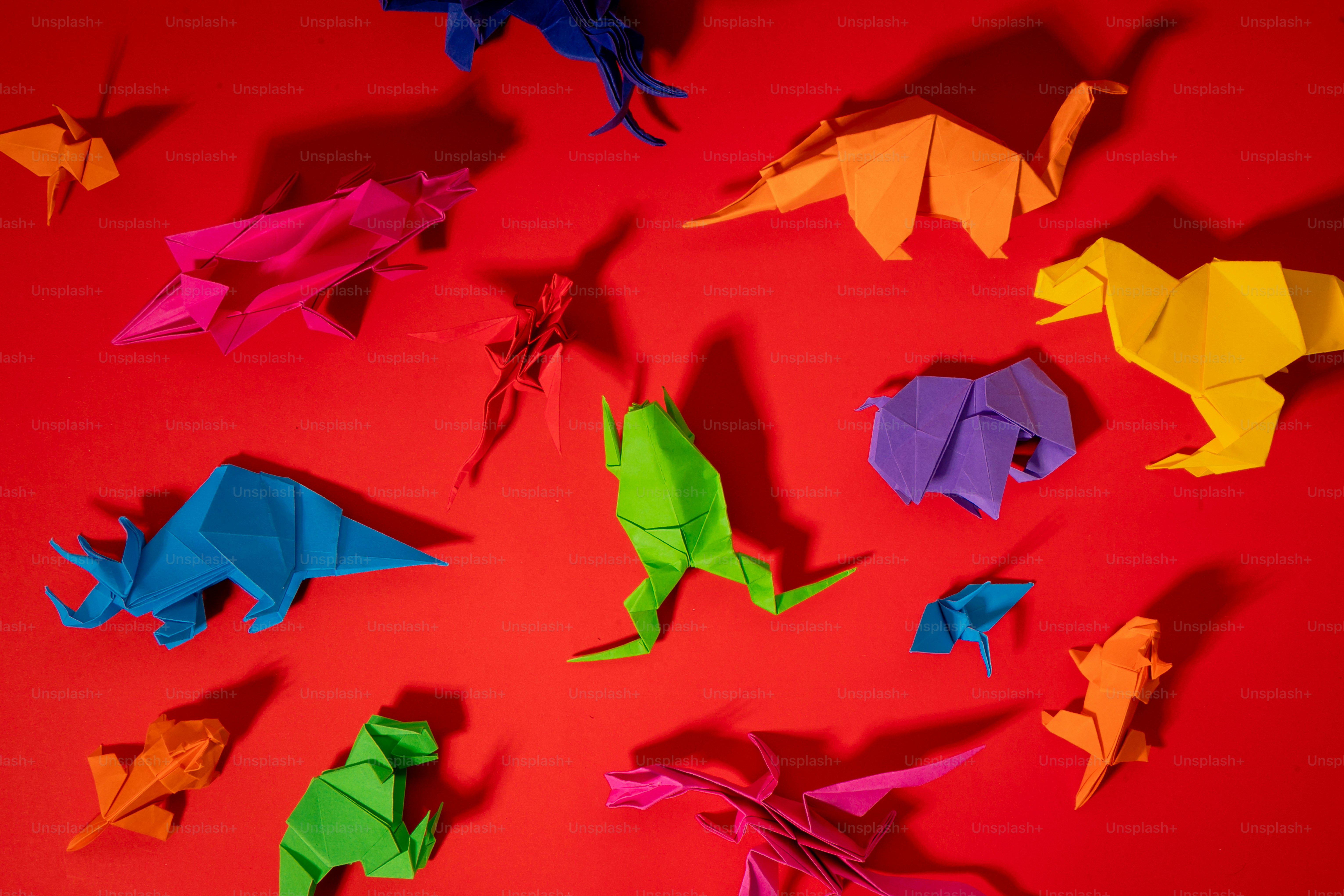 Sekelompok dinosaurus origami dengan latar belakang merah