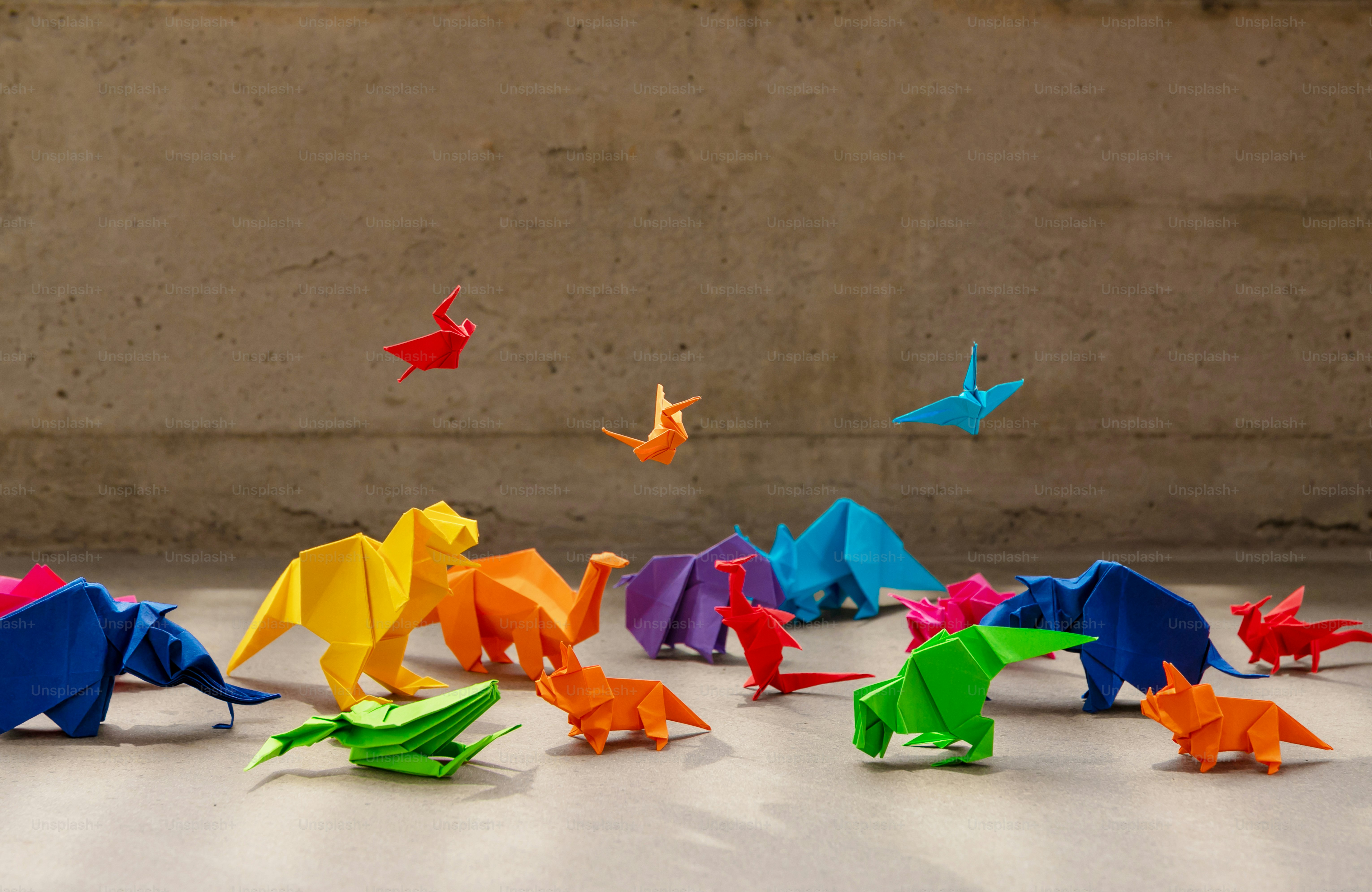 Sekelompok dinosaurus origami berwarna-warni di tanah