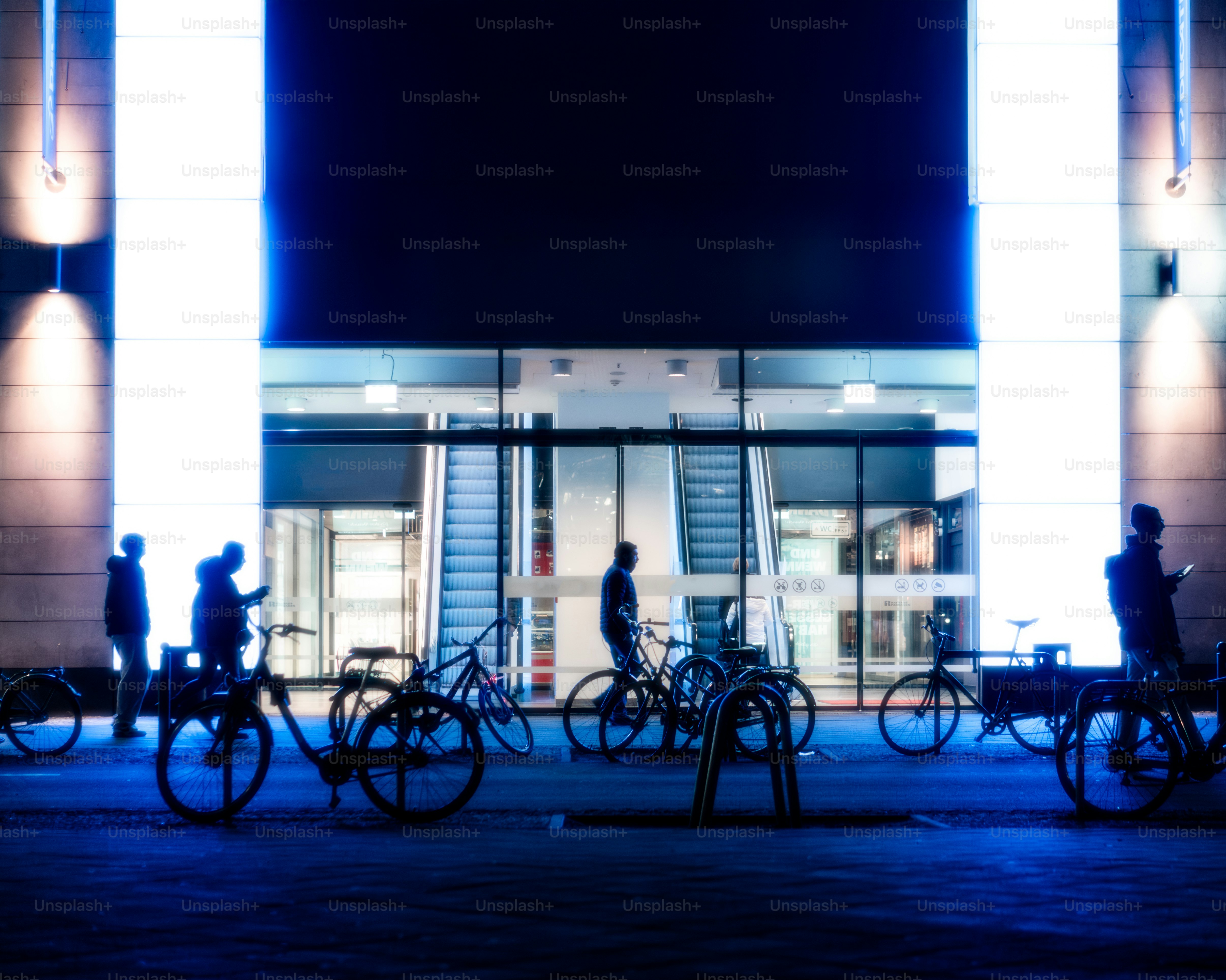 A group of people riding bikes past a tall building