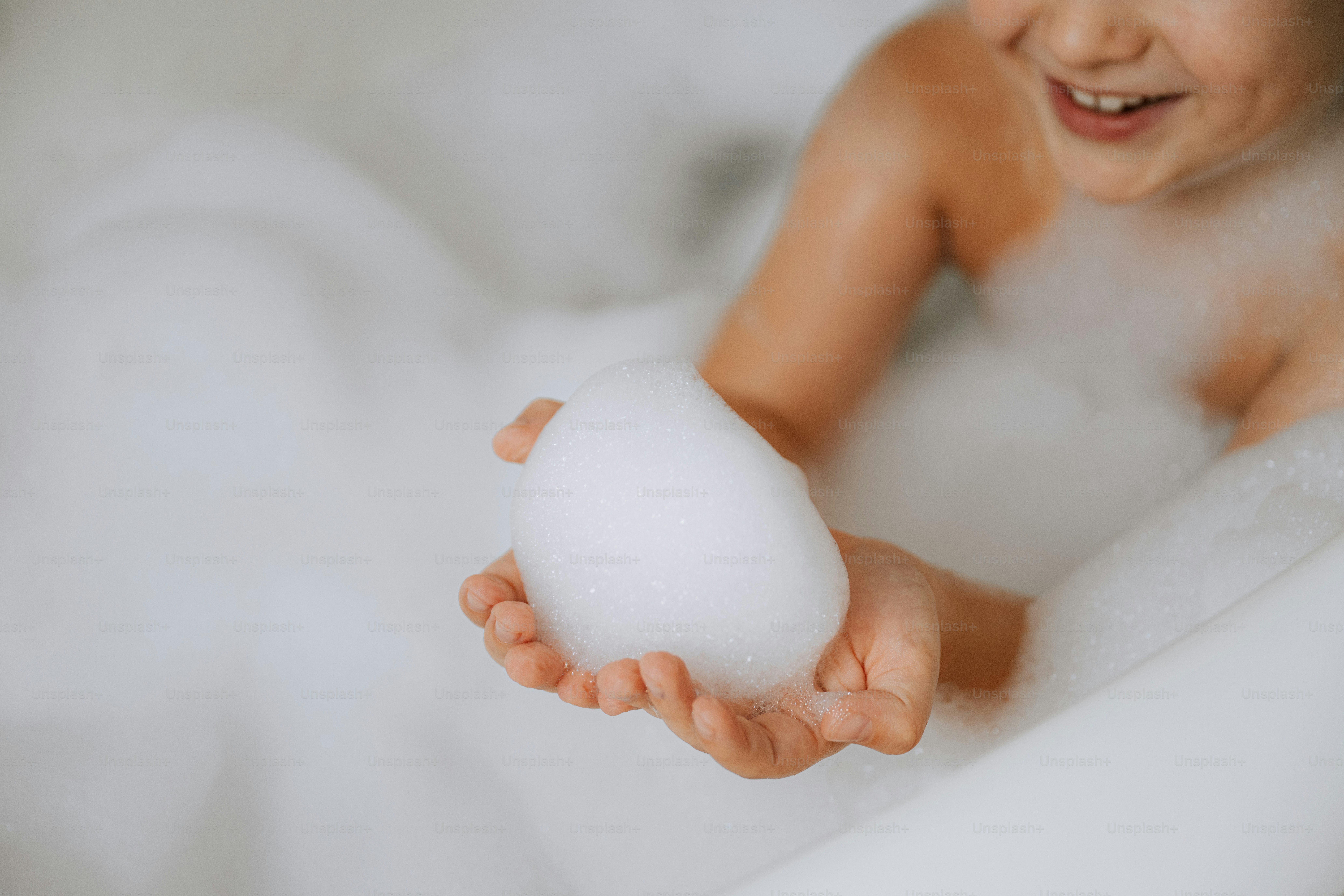 A baby in a bathtub holding a foam ball
