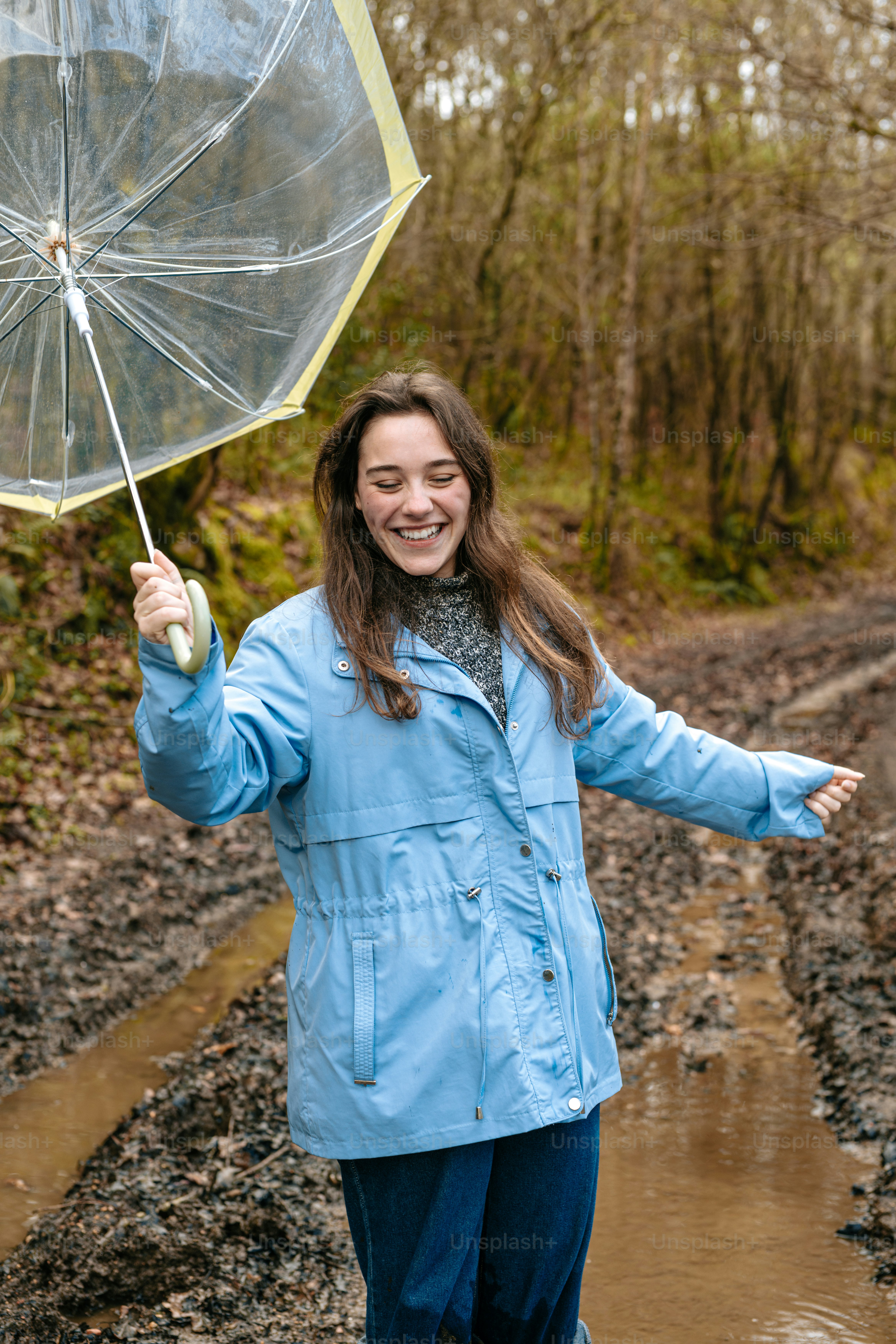 A woman in a blue coat is holding an umbrella