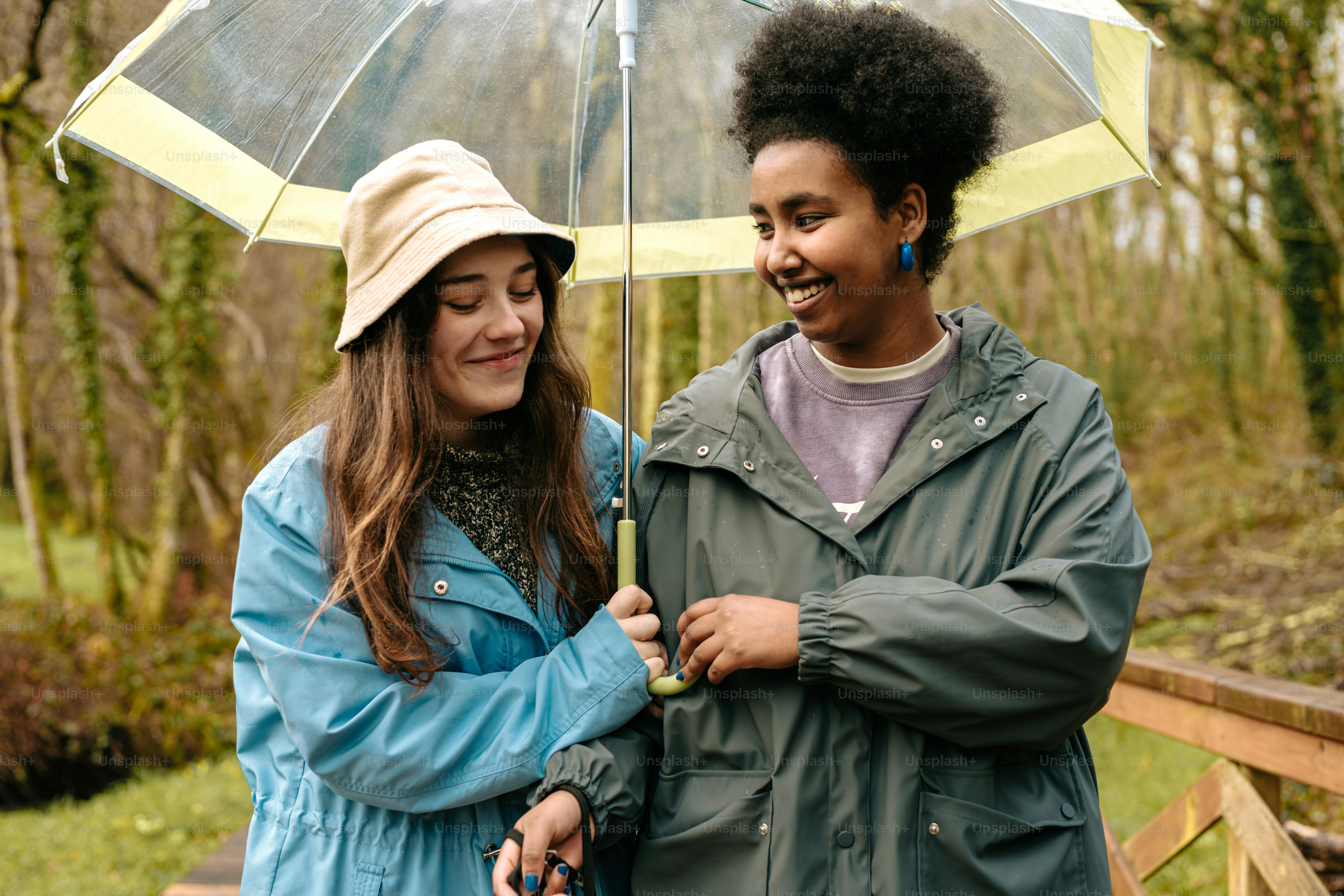 A couple of women standing next to each other under an umbrella