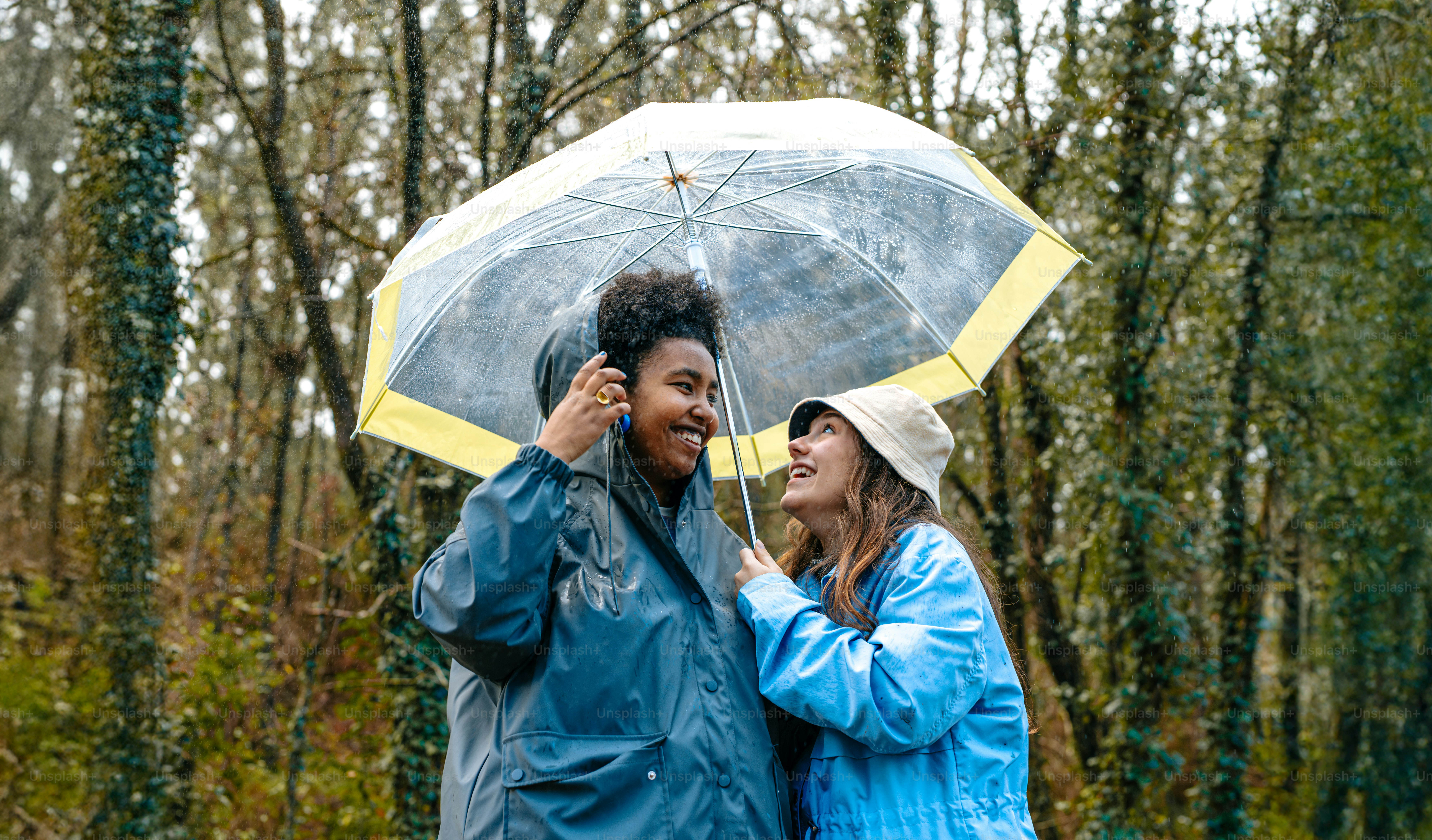 A couple of women standing next to each other under an umbrella