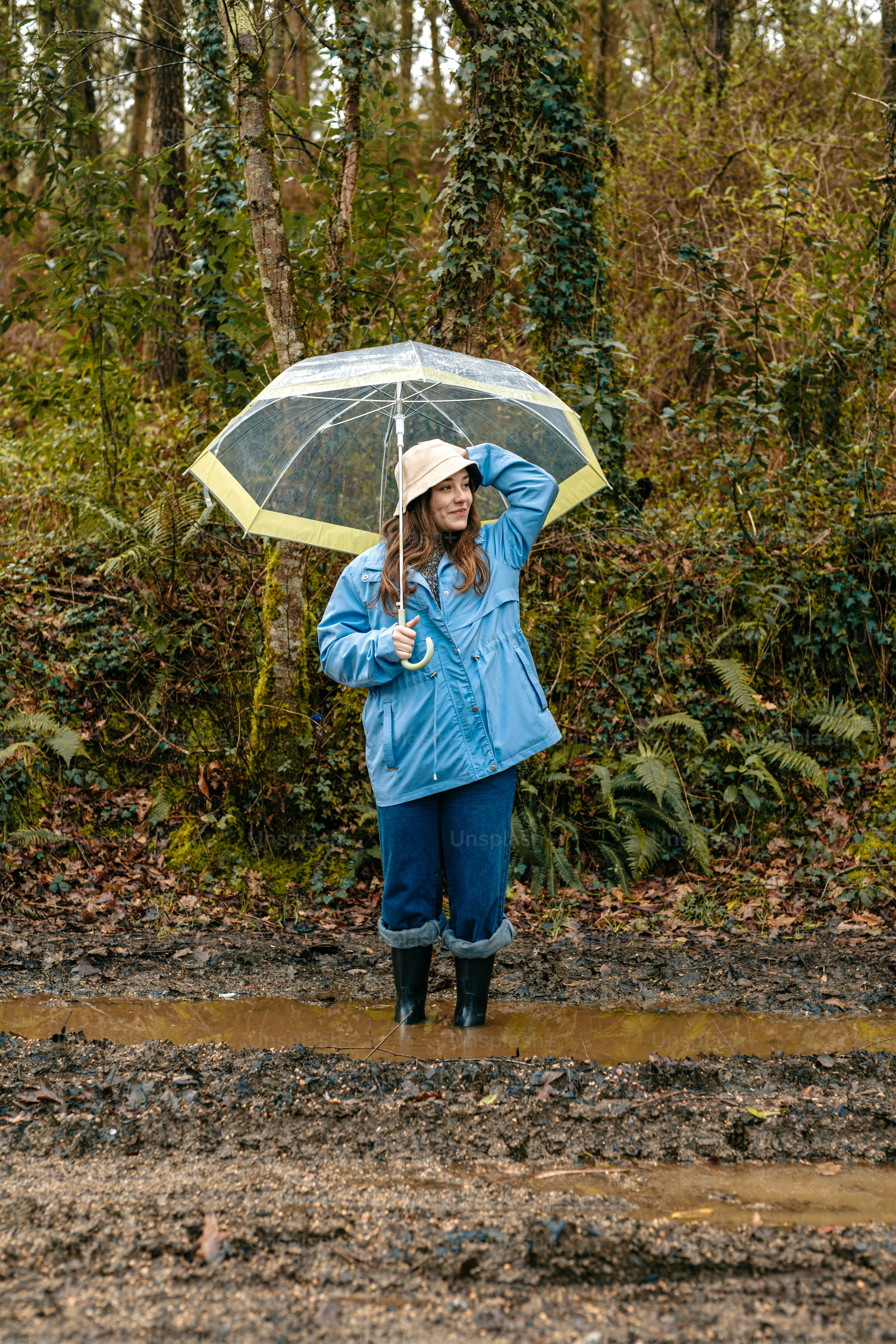 A woman standing in the mud holding an umbrella