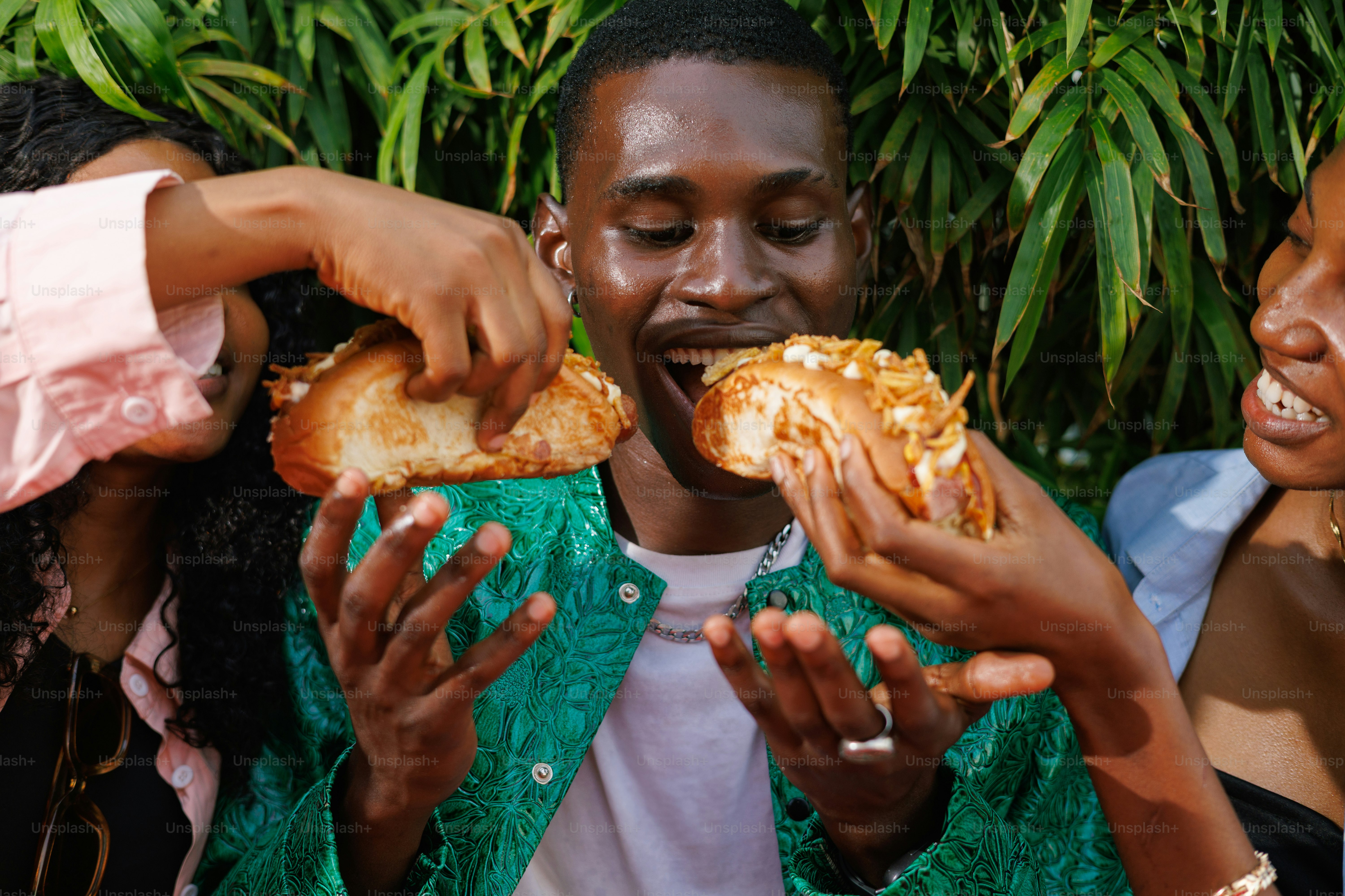 A group of people standing around each other eating food photo – Food ...