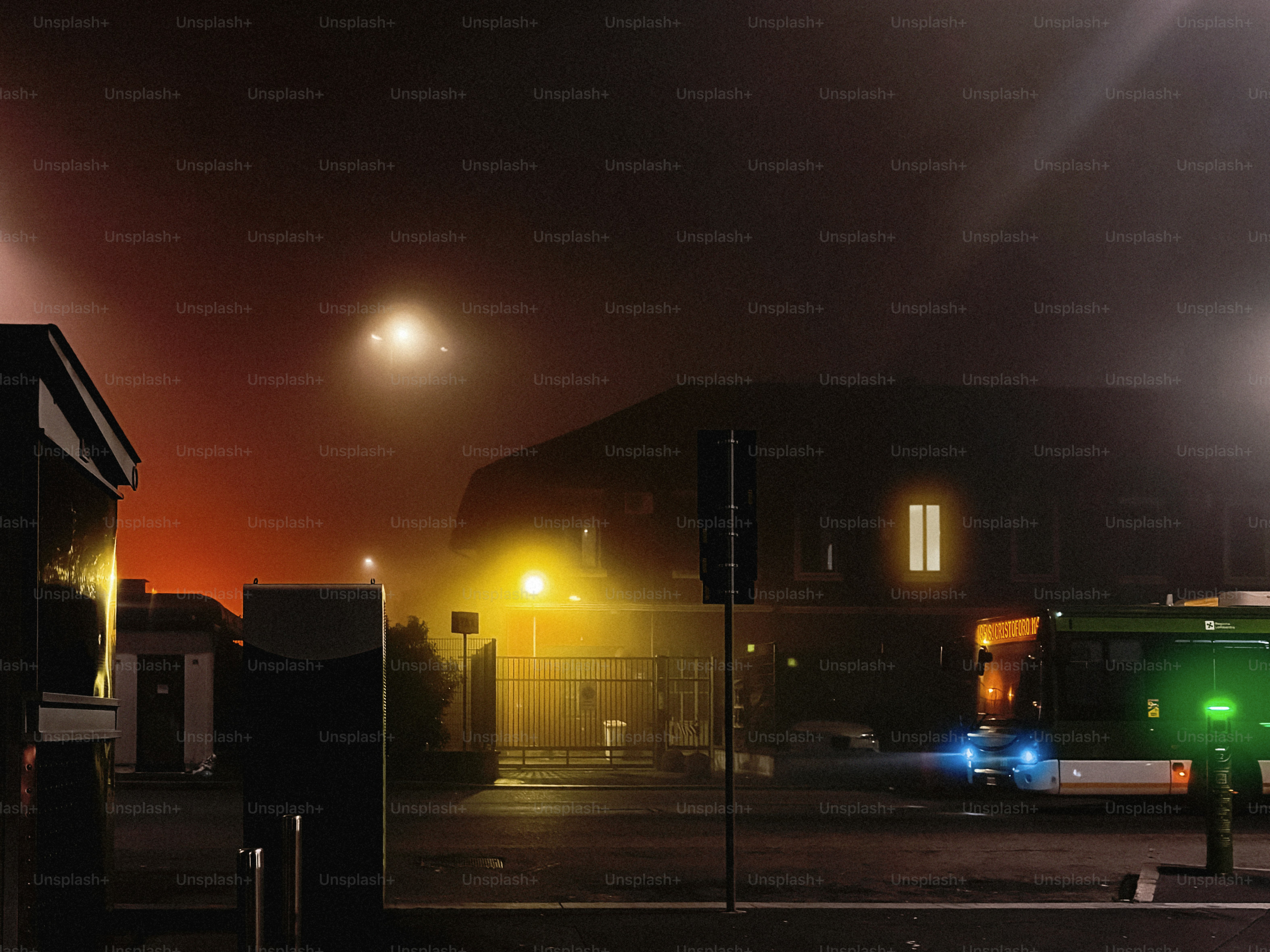 A green bus driving down a street at night