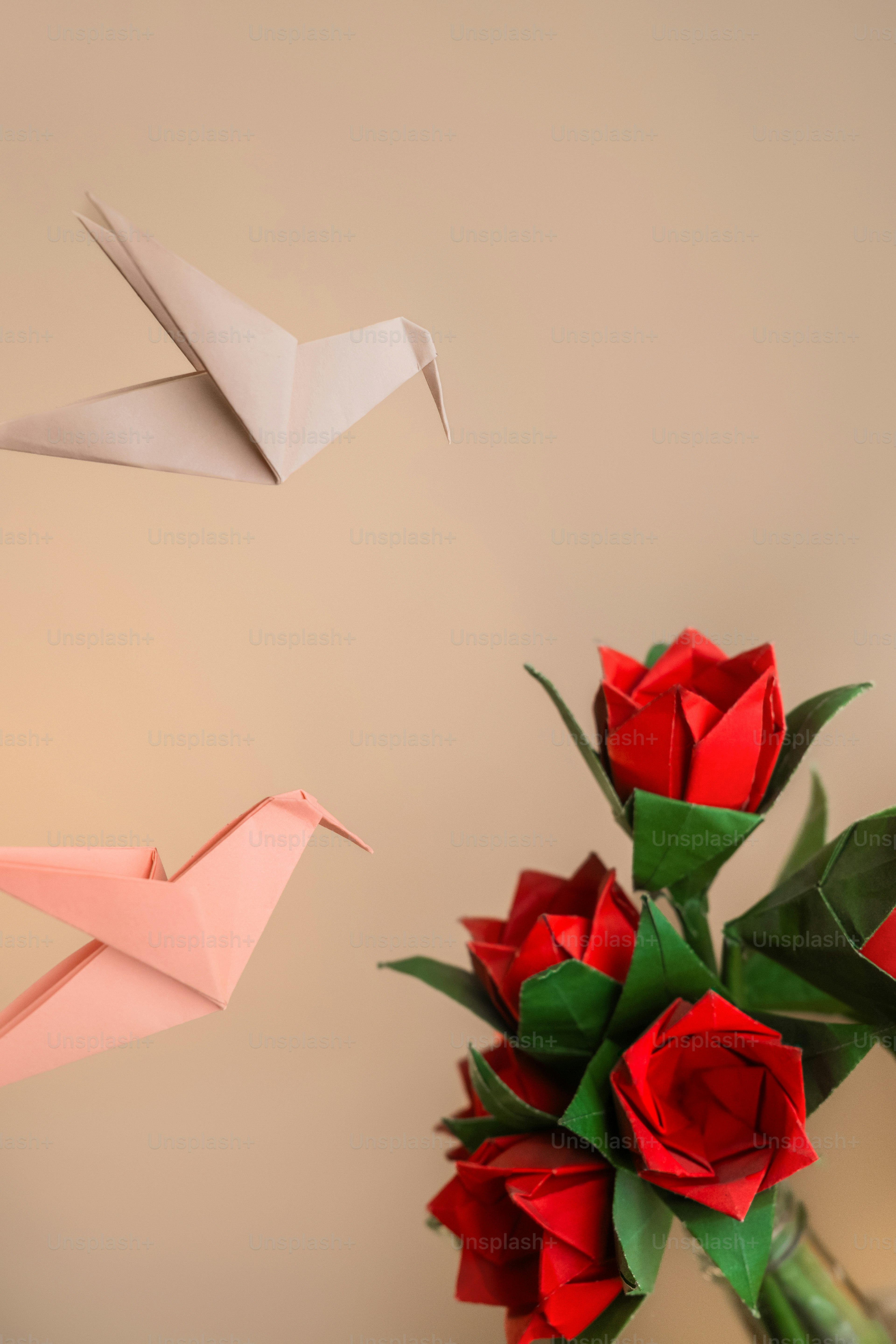 Two origami birds and a vase of roses