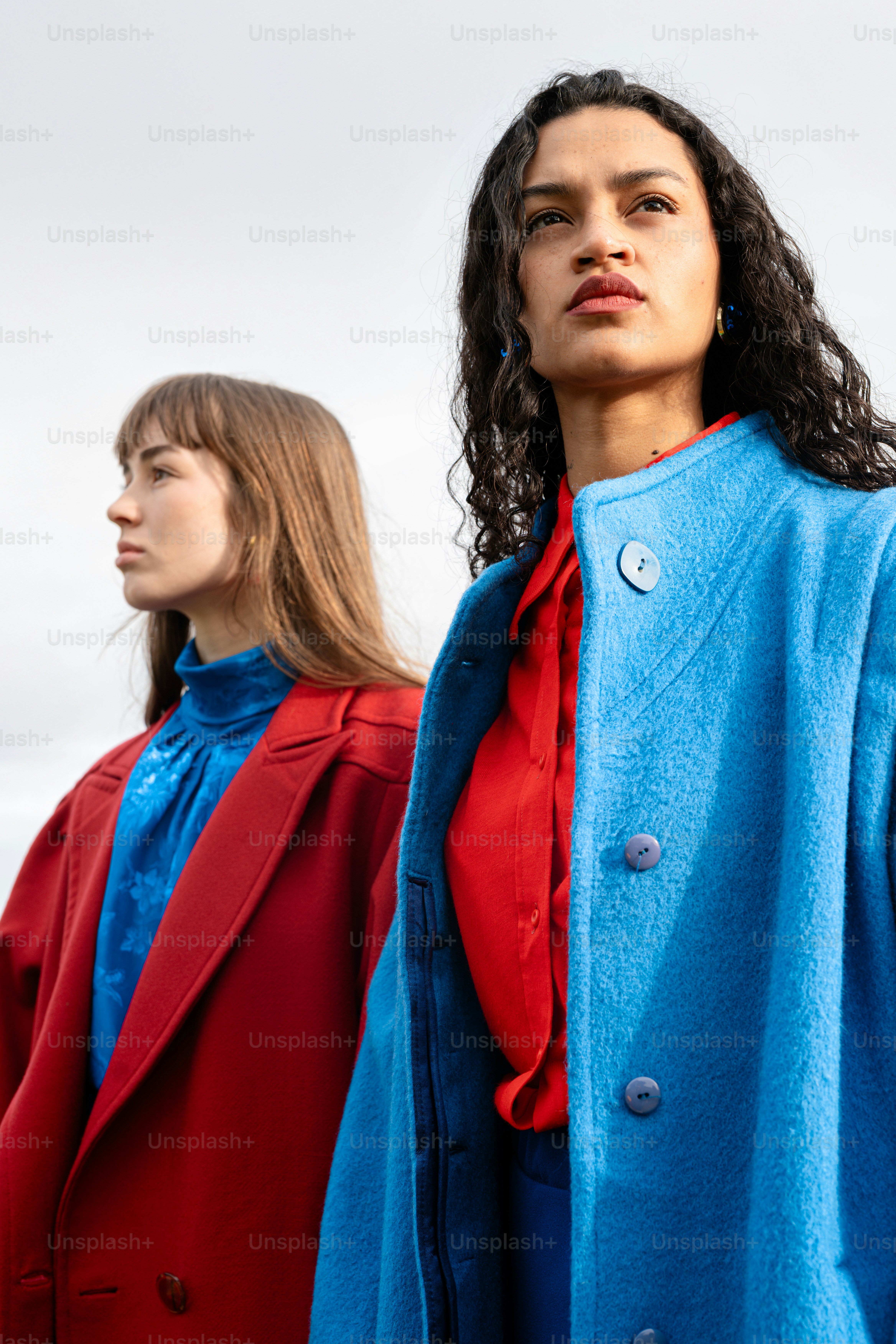 Two women standing next to each other wearing coats