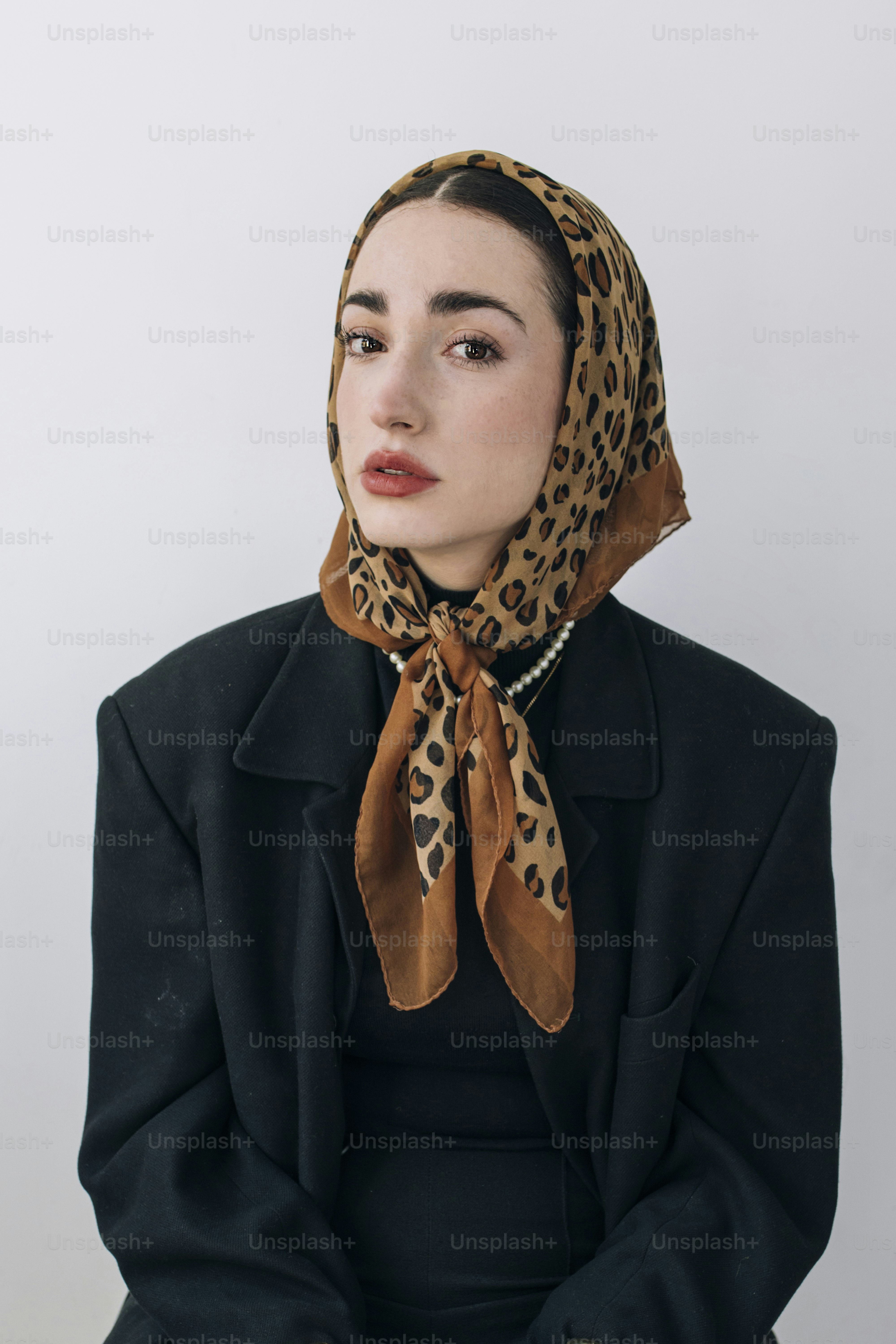 Eine Frau trägt einen schwarzen Mantel und einen Schal mit Leopardenmuster