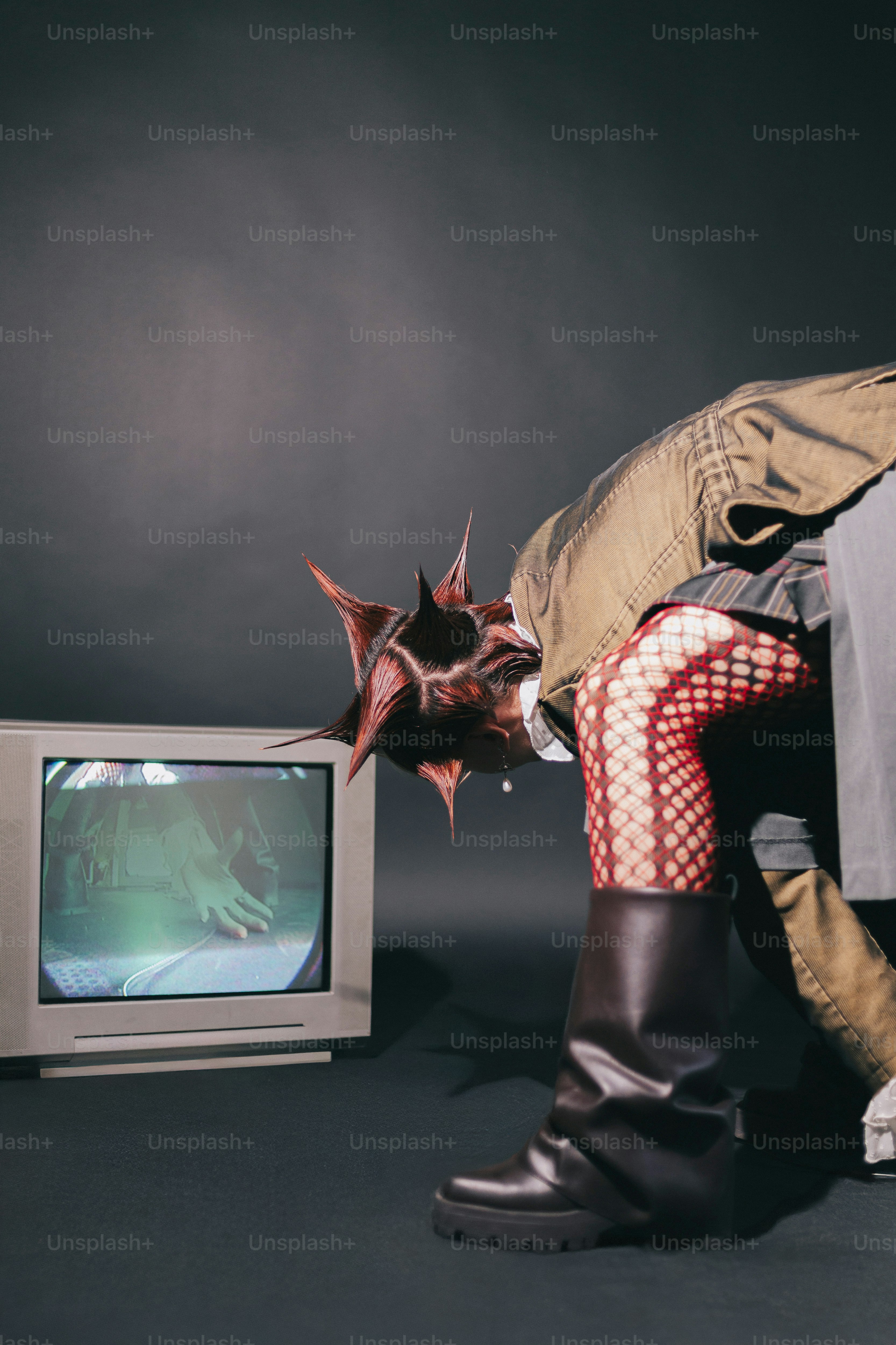 Um homem está se curvando para olhar para uma televisão