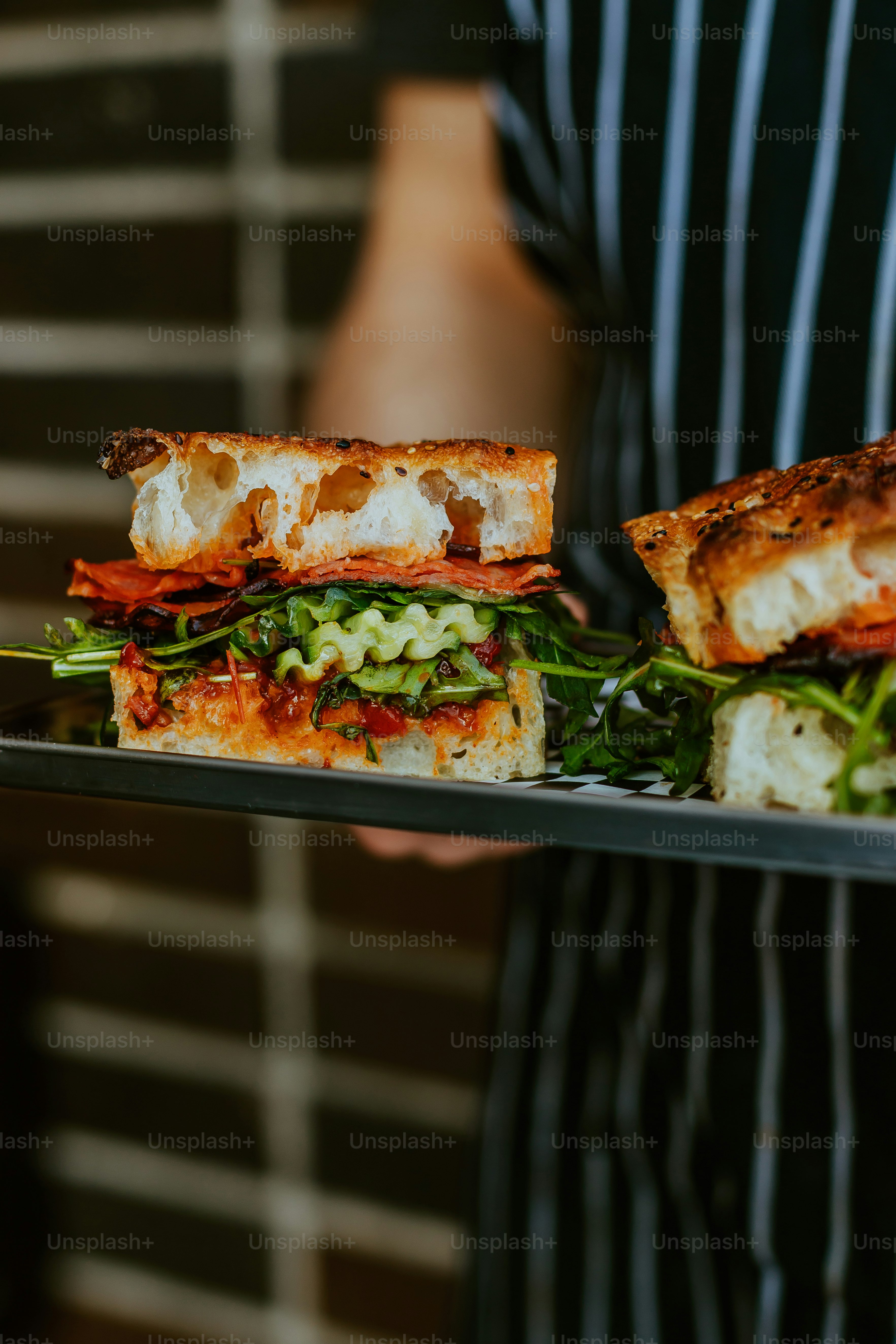 Una persona sosteniendo una bandeja con sándwiches