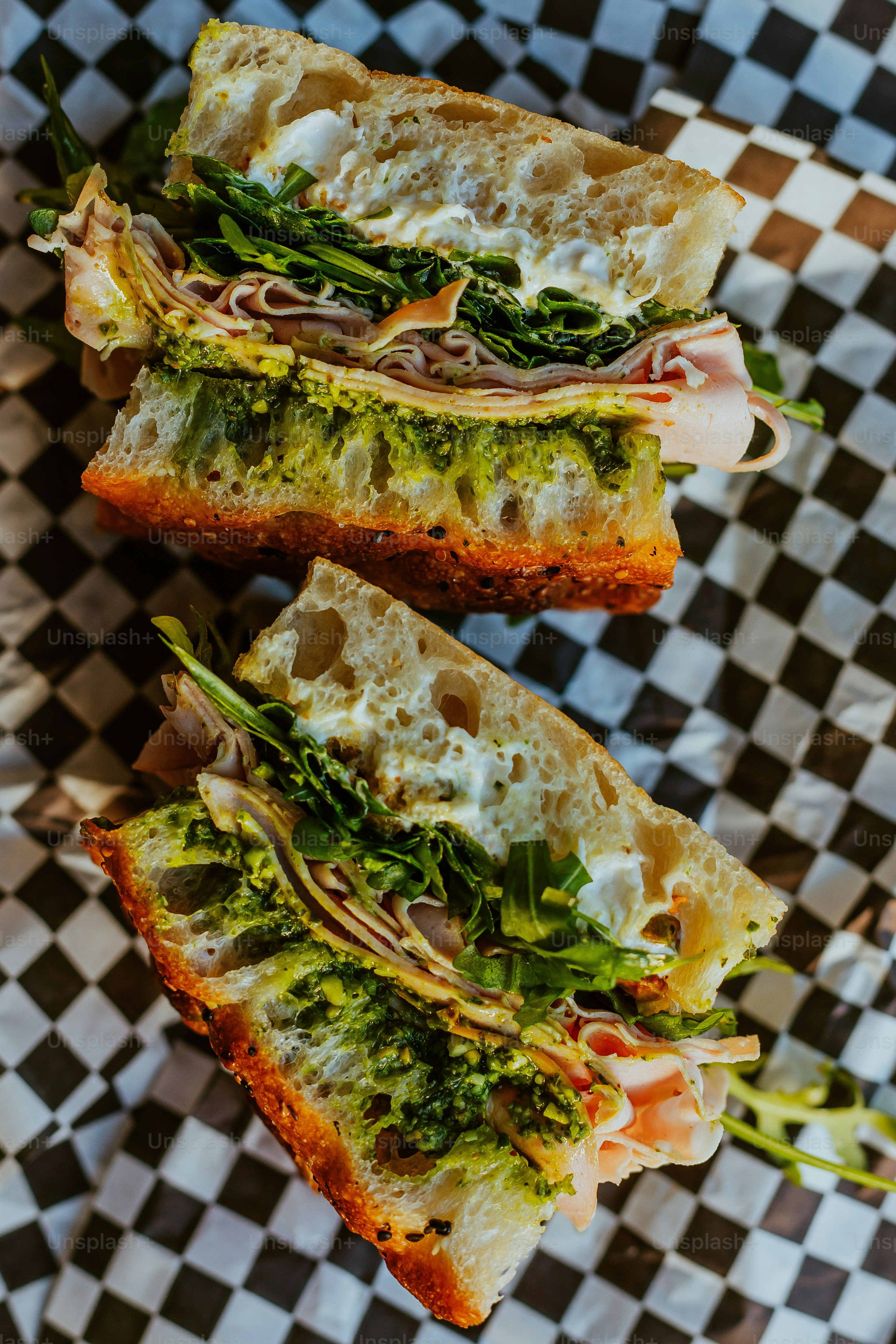 A sandwich cut in half sitting on top of a checkered paper